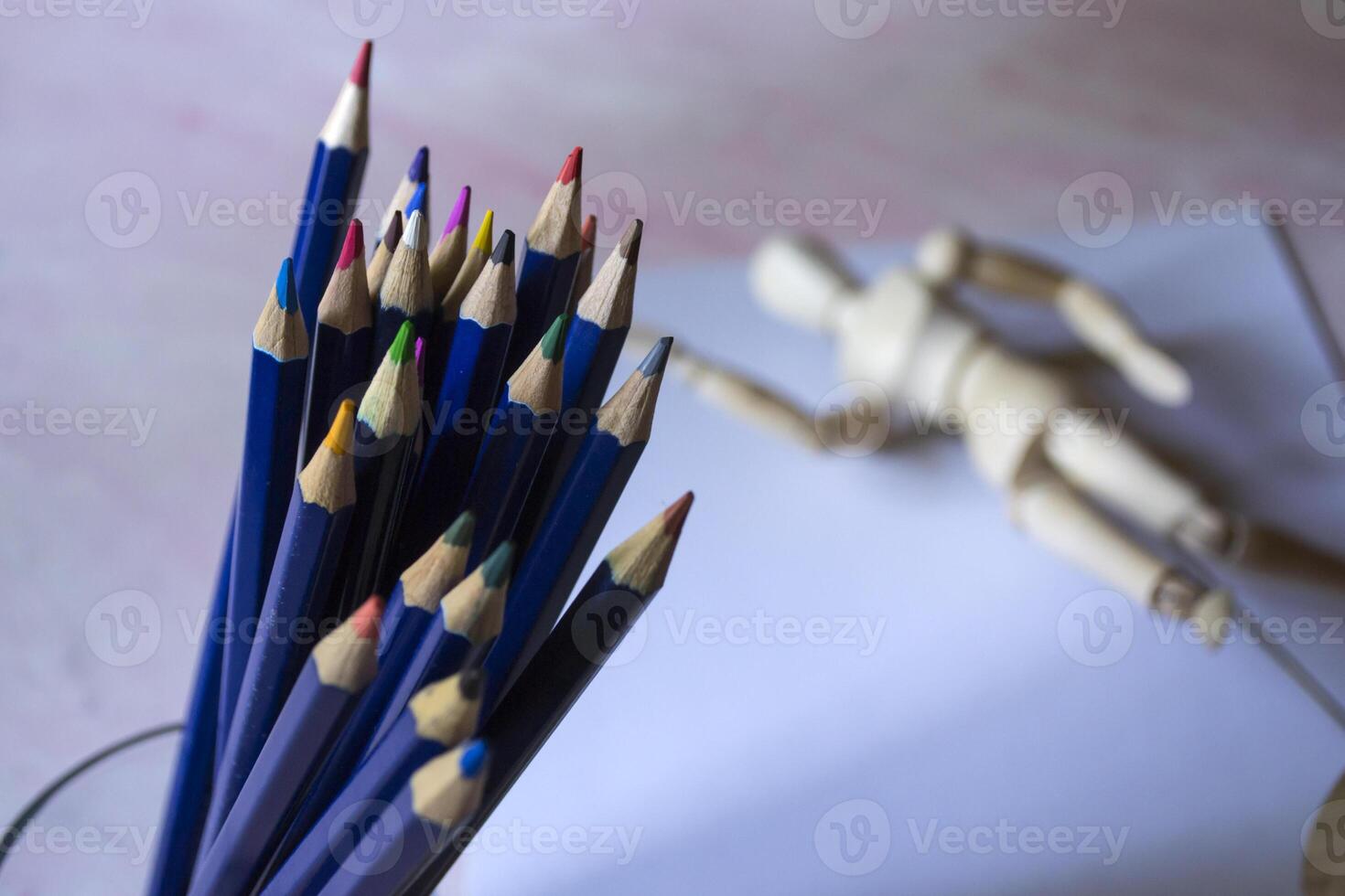 Colored pencils, empty paper and dummy for drawing on the table. photo