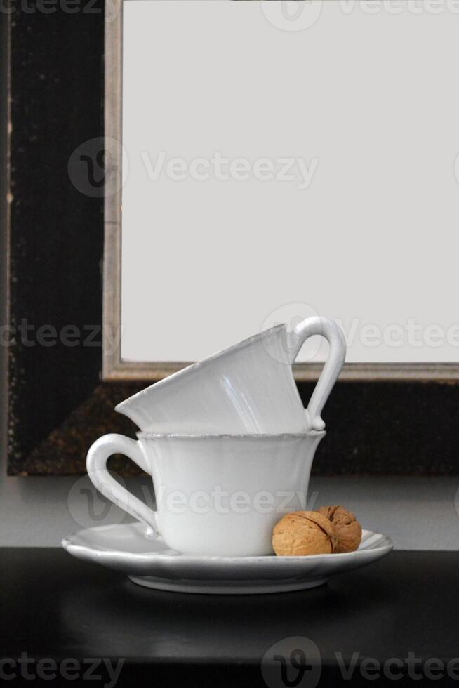 Tea cups on a table against a white sheet background in a frame. photo