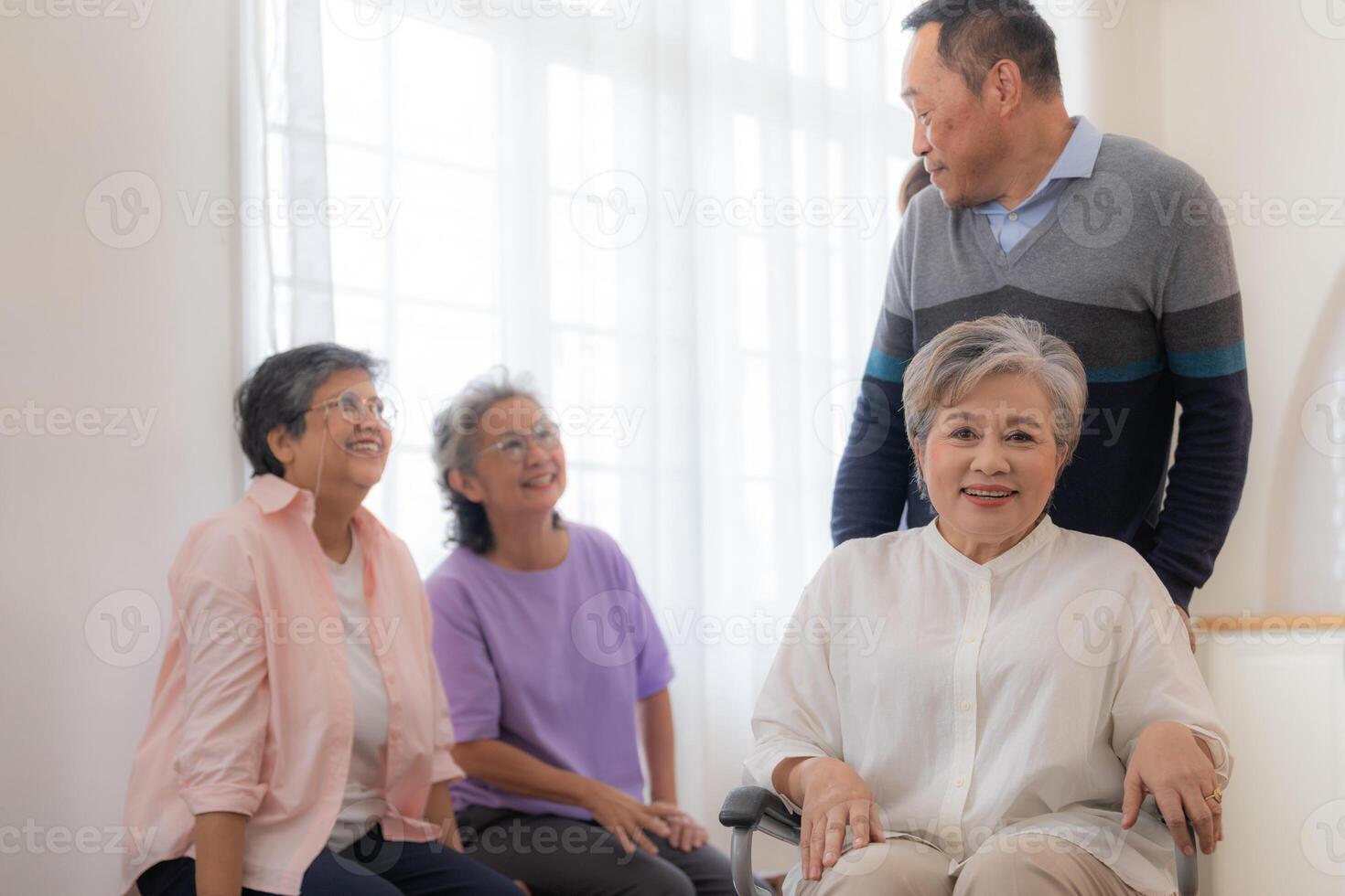 Asian young nurse support couple senior older man and woman in a wheelchair. elderly mature and a group of senior friends living in the hospital. socializing of retired people. photo