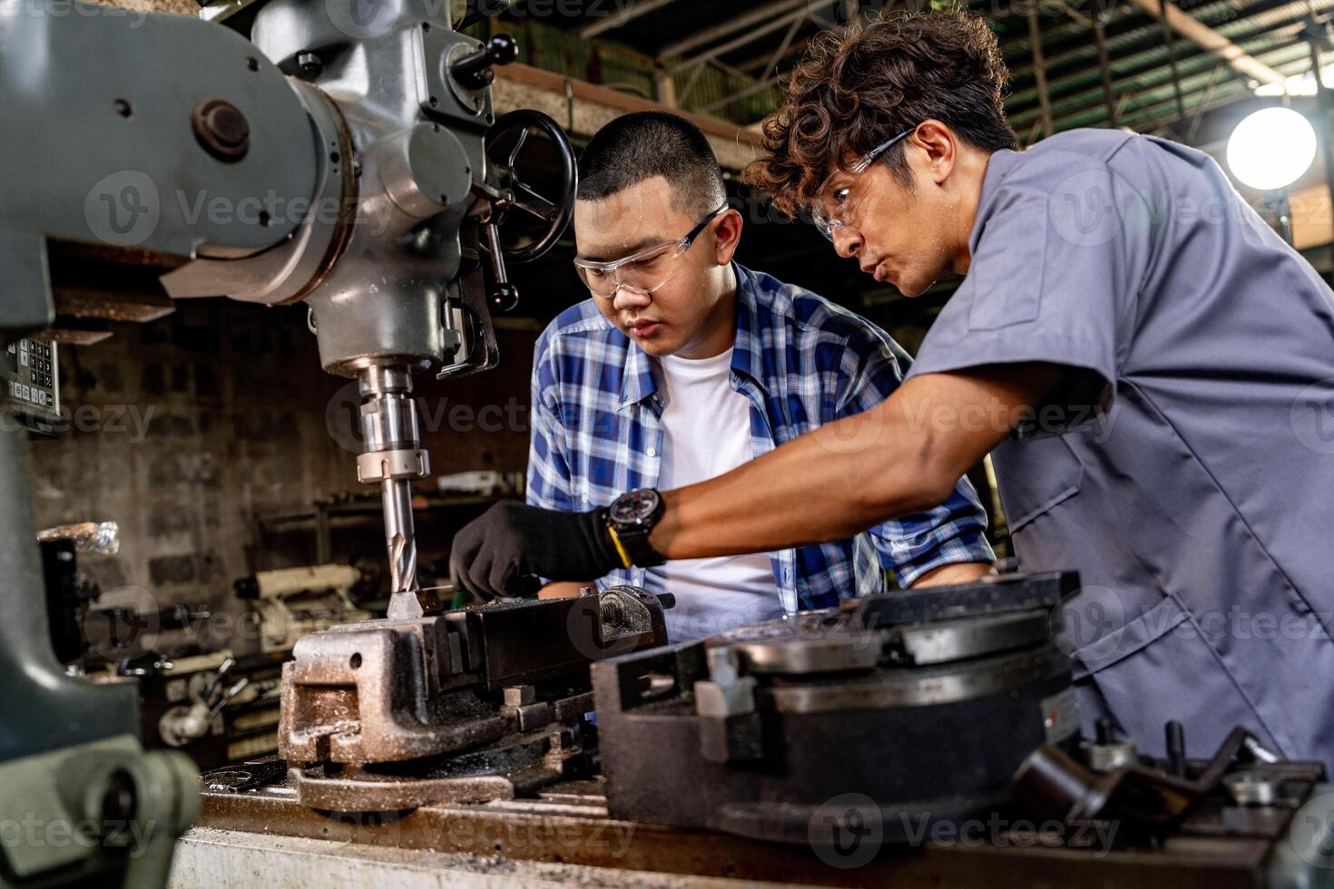 Asian worker in production plant drilling at machine. Professional worker near drilling machine on factory. finishing metal working internal steel surface on lathe grinder machine with flying sparks. photo