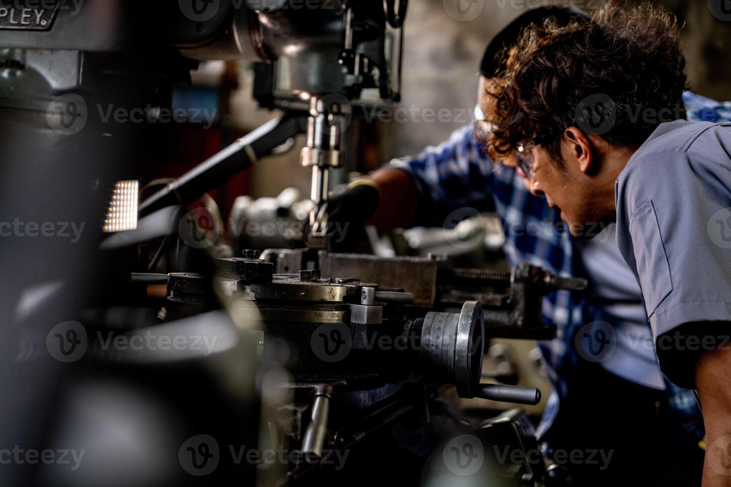 Asian worker in production plant drilling at machine. Professional worker near drilling machine on factory. finishing metal working internal steel surface on lathe grinder machine with flying sparks. photo