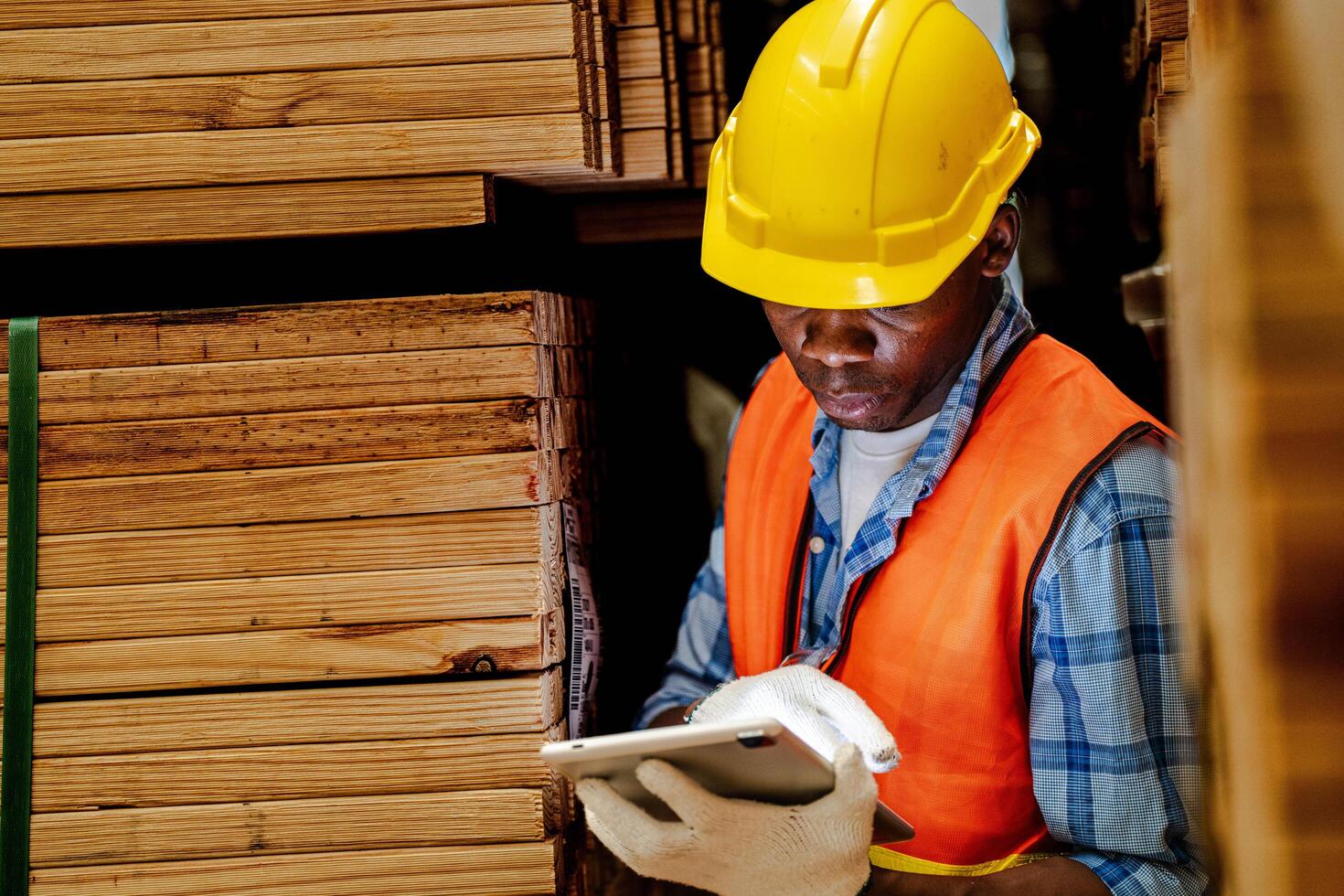 African worker carpenter wearing safety uniform and hard hat working and checking the quality of wooden products at workshop manufacturing. man and woman workers wood in dark warehouse industry. photo