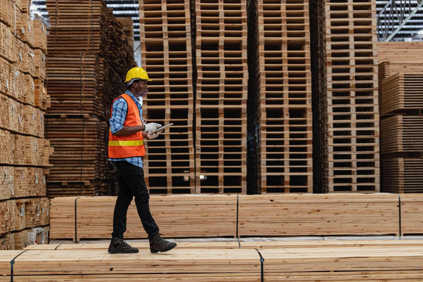 africano trabajadores hombre Ingenieria caminando y inspeccionando con trabajando suite vestir y mano guante en madera madera depósito. concepto de inteligente industria trabajador operando. madera suerte Produce madera paladar. foto