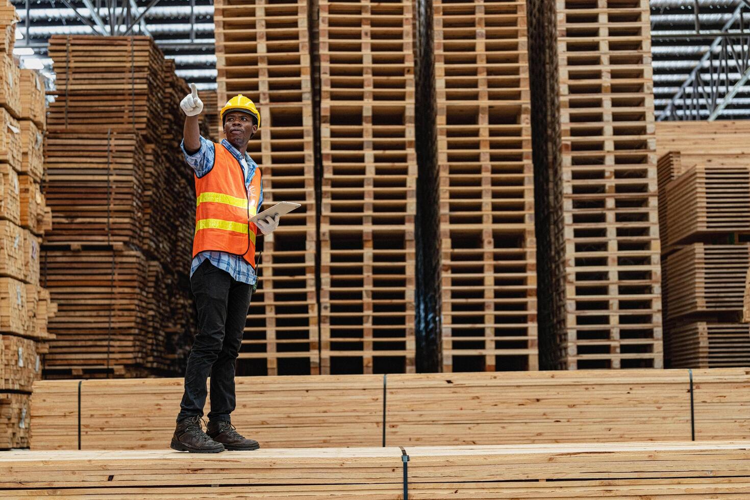 African workers man engineering walking and inspecting with working suite dress and hand glove in timber wood warehouse. Concept of smart industry worker operating. Wood factories produce wood palate. photo