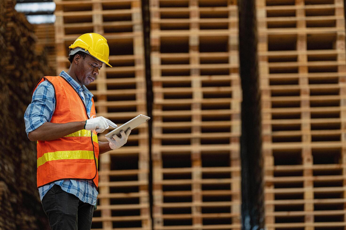 African workers man engineering walking and inspecting with working suite dress and hand glove in timber wood warehouse. Concept of smart industry worker operating. Wood factories produce wood palate. photo