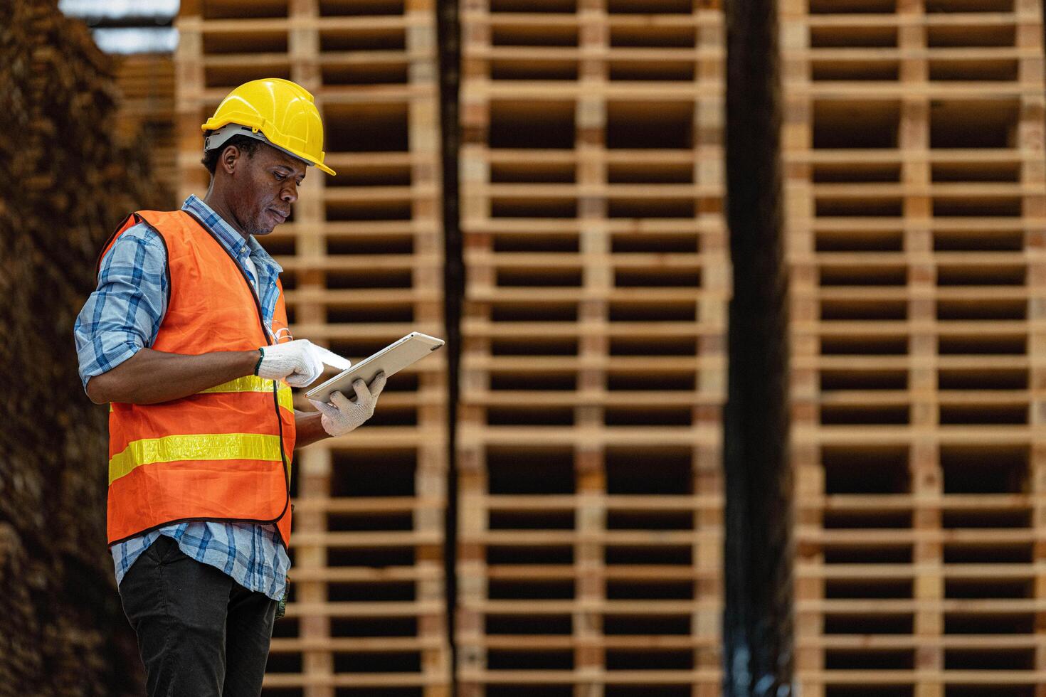 African workers man engineering walking and inspecting with working suite dress and hand glove in timber wood warehouse. Concept of smart industry worker operating. Wood factories produce wood palate. photo