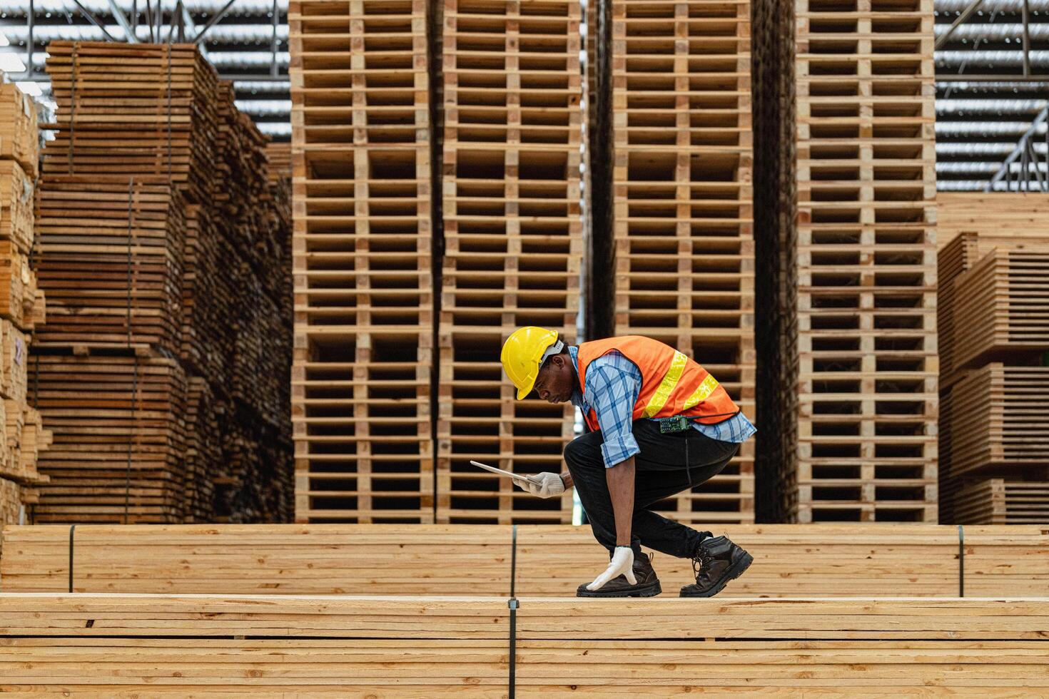 African workers man engineering walking and inspecting with working suite dress and hand glove in timber wood warehouse. Concept of smart industry worker operating. Wood factories produce wood palate. photo