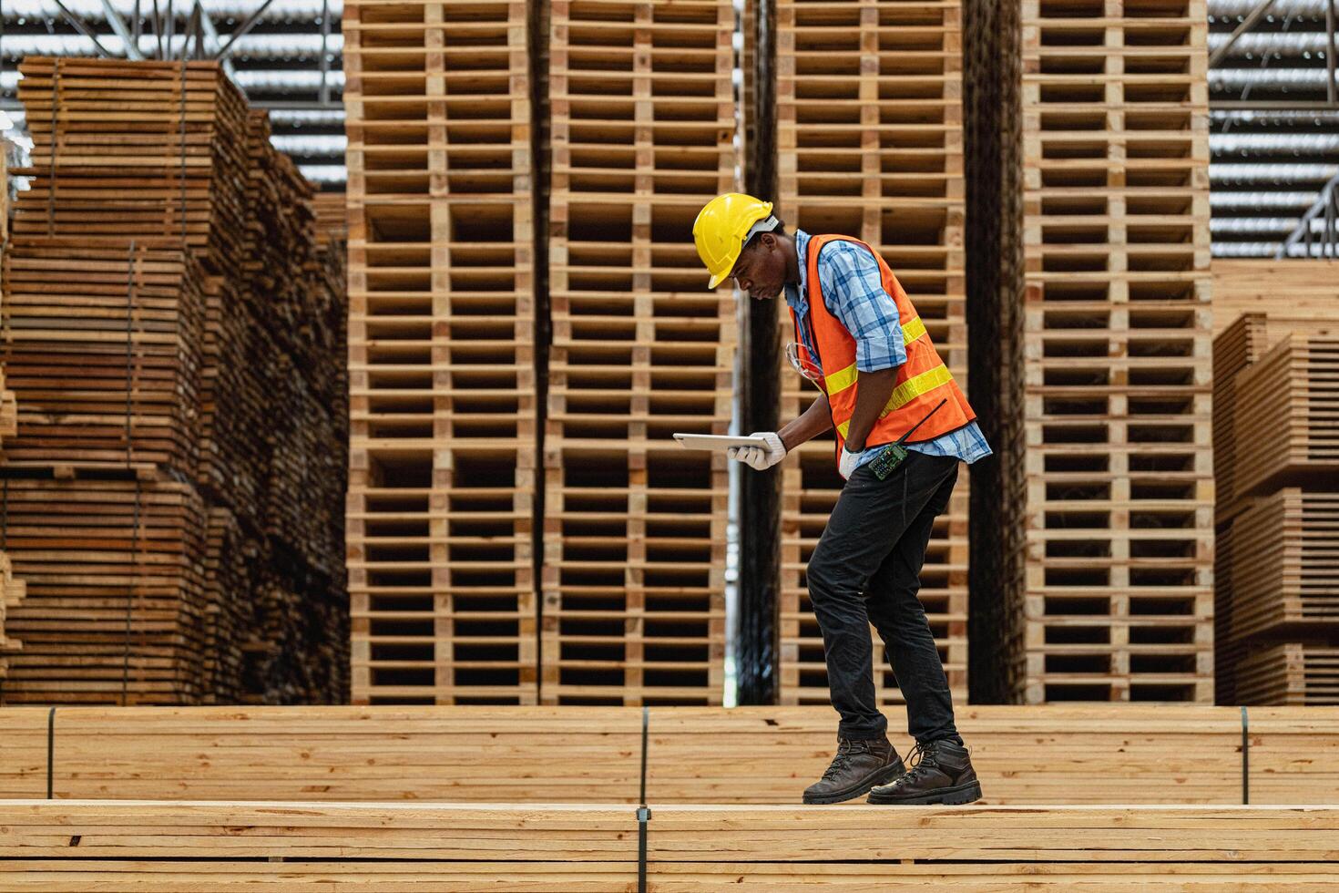 African workers man engineering walking and inspecting with working suite dress and hand glove in timber wood warehouse. Concept of smart industry worker operating. Wood factories produce wood palate. photo