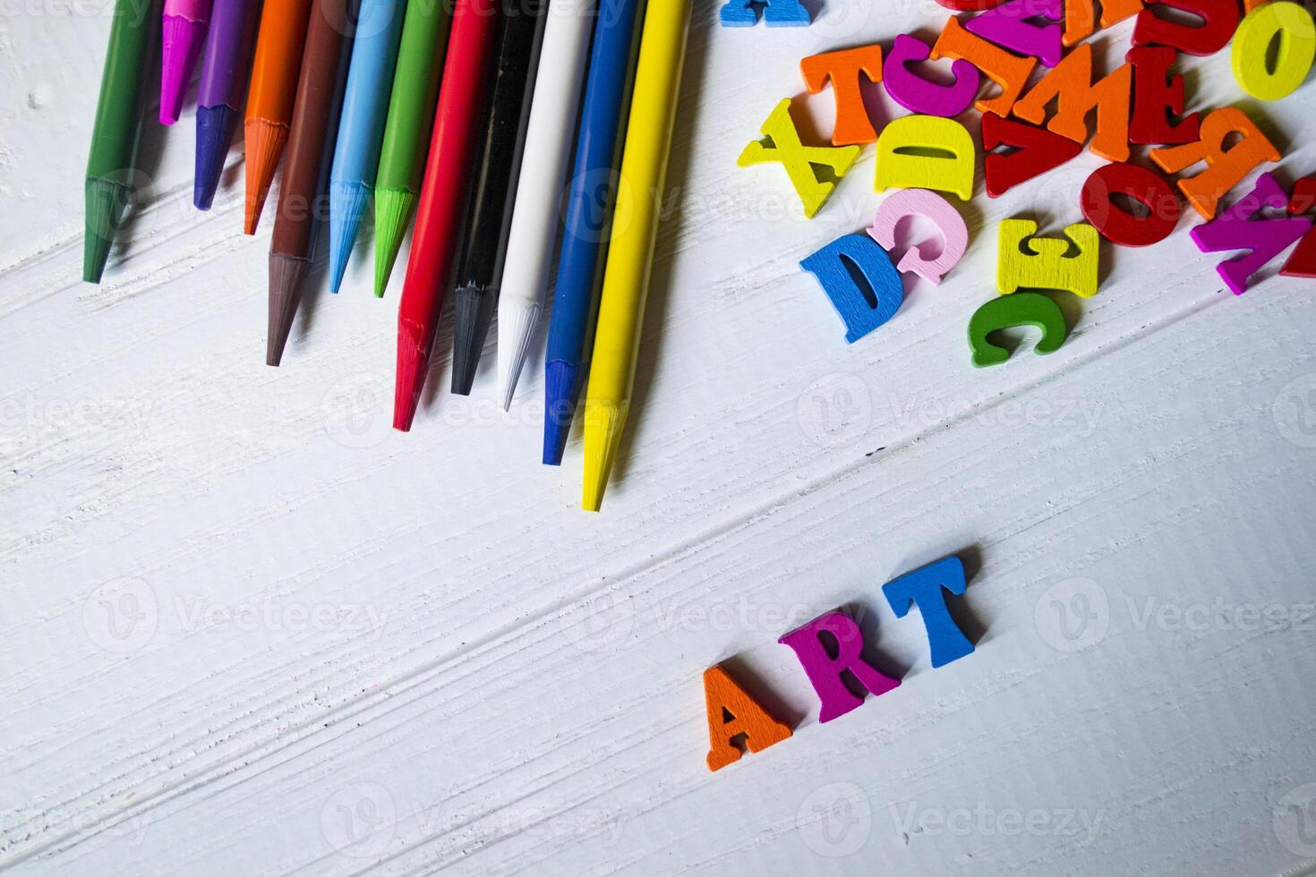 Multicolor letters and set of pencils on the table. Colorful wooden alphabet and pencils on a table. photo