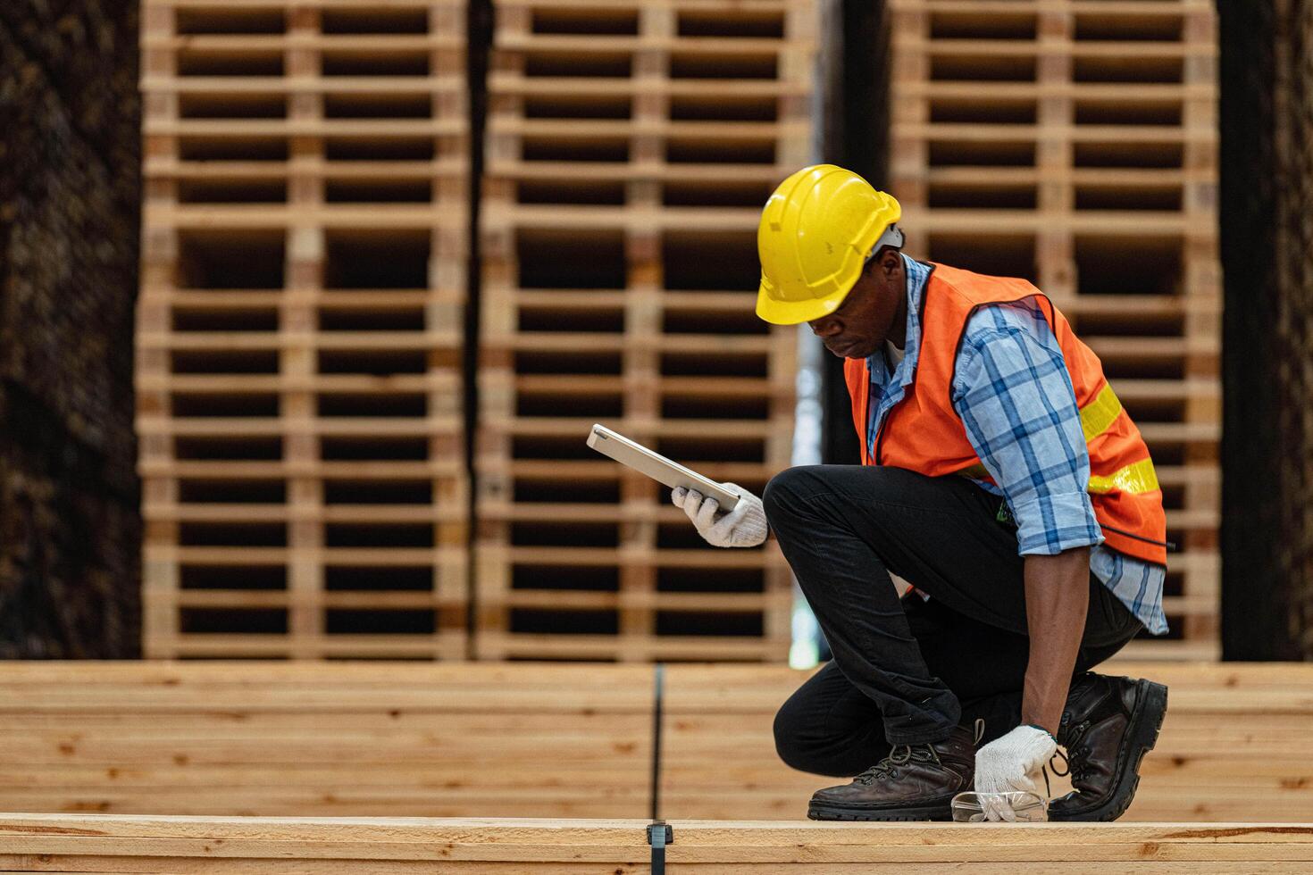 African workers man engineering walking and inspecting with working suite dress and hand glove in timber wood warehouse. Concept of smart industry worker operating. Wood factories produce wood palate. photo