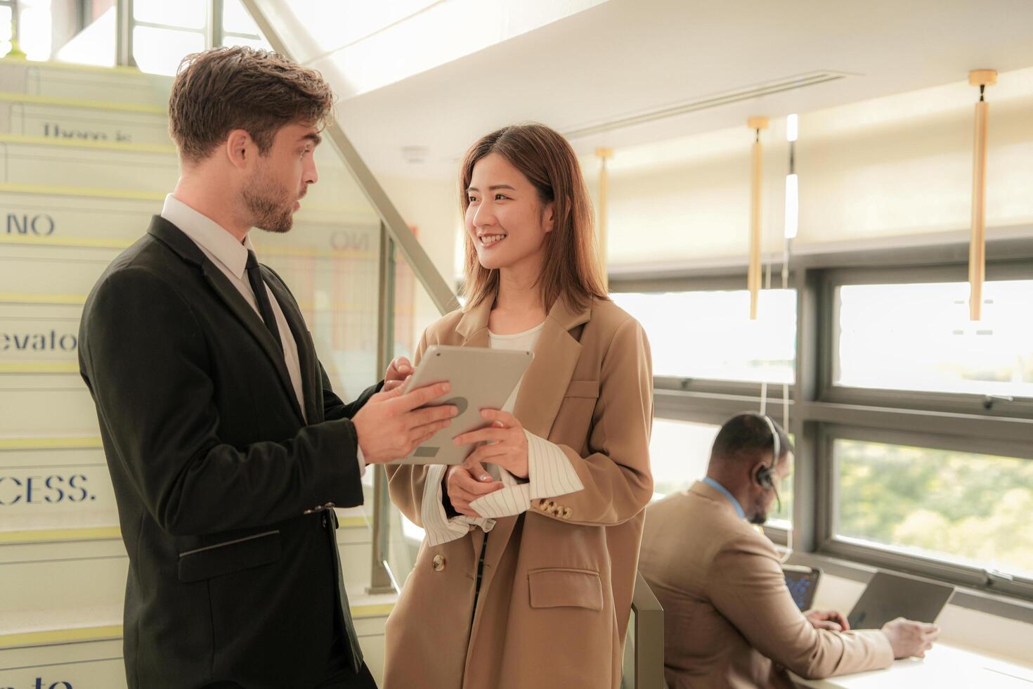 business people lady and caucasian smart man with smart tablet and talk presentation at indoor stairs way. team of business people walk in rush hour at indoor pedestrian stairs and talk together. photo