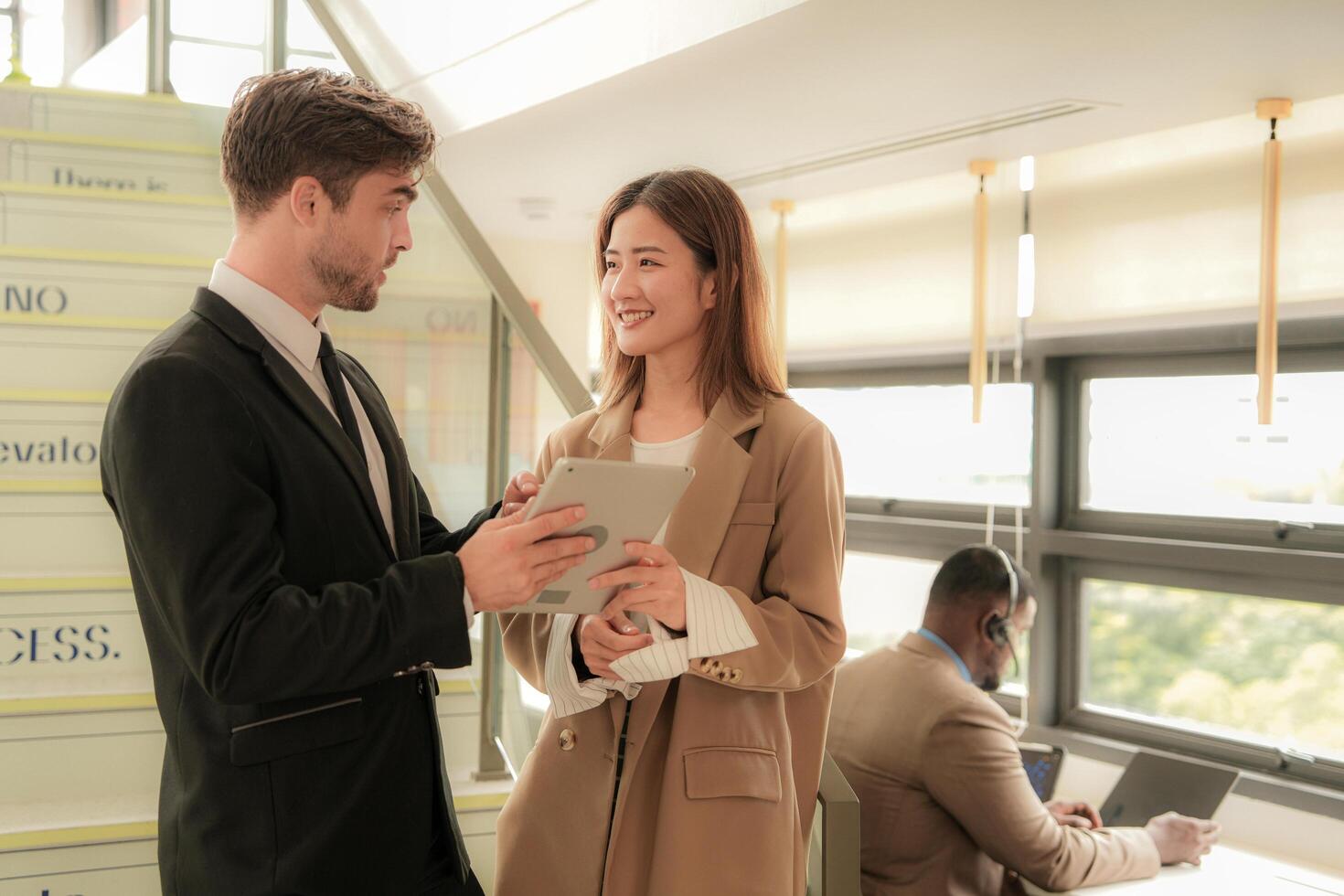business people lady and caucasian smart man with smart tablet and talk presentation at indoor stairs way. team of business people walk in rush hour at indoor pedestrian stairs and talk together. photo