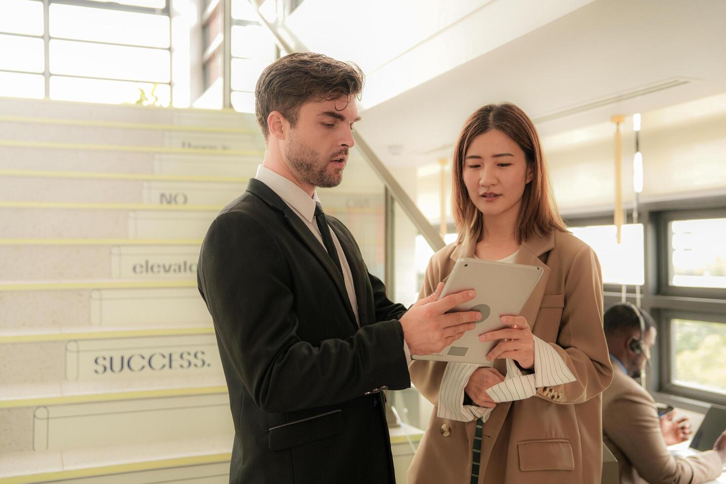 business people lady and caucasian smart man with smart tablet and talk presentation at indoor stairs way. team of business people walk in rush hour at indoor pedestrian stairs and talk together. photo