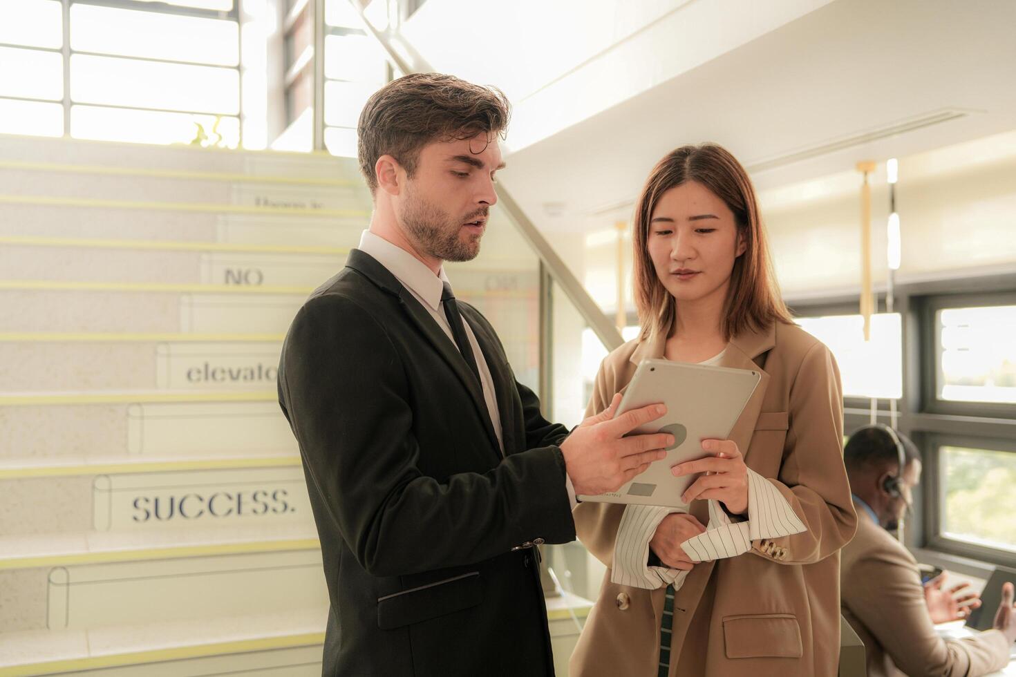 business people lady and caucasian smart man with smart tablet and talk presentation at indoor stairs way. team of business people walk in rush hour at indoor pedestrian stairs and talk together. photo