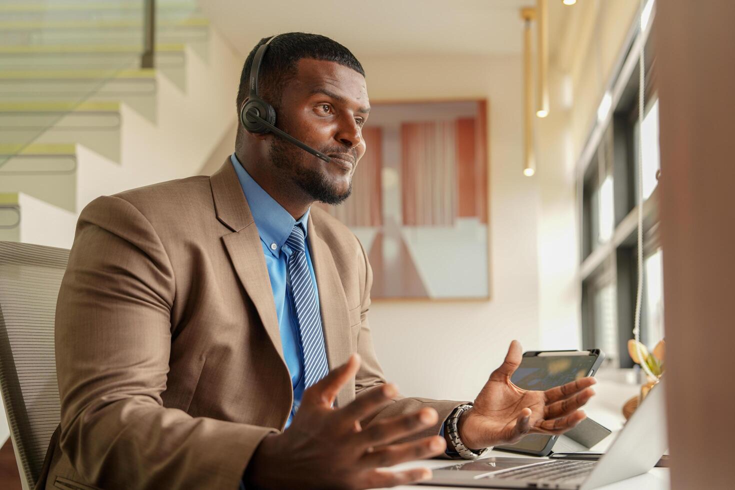 Customer Support Call Center Operator Or Receptionist. customer service and man consultant talking while doing a consultation online. African operator male telemarketing agent on a laptop in office photo