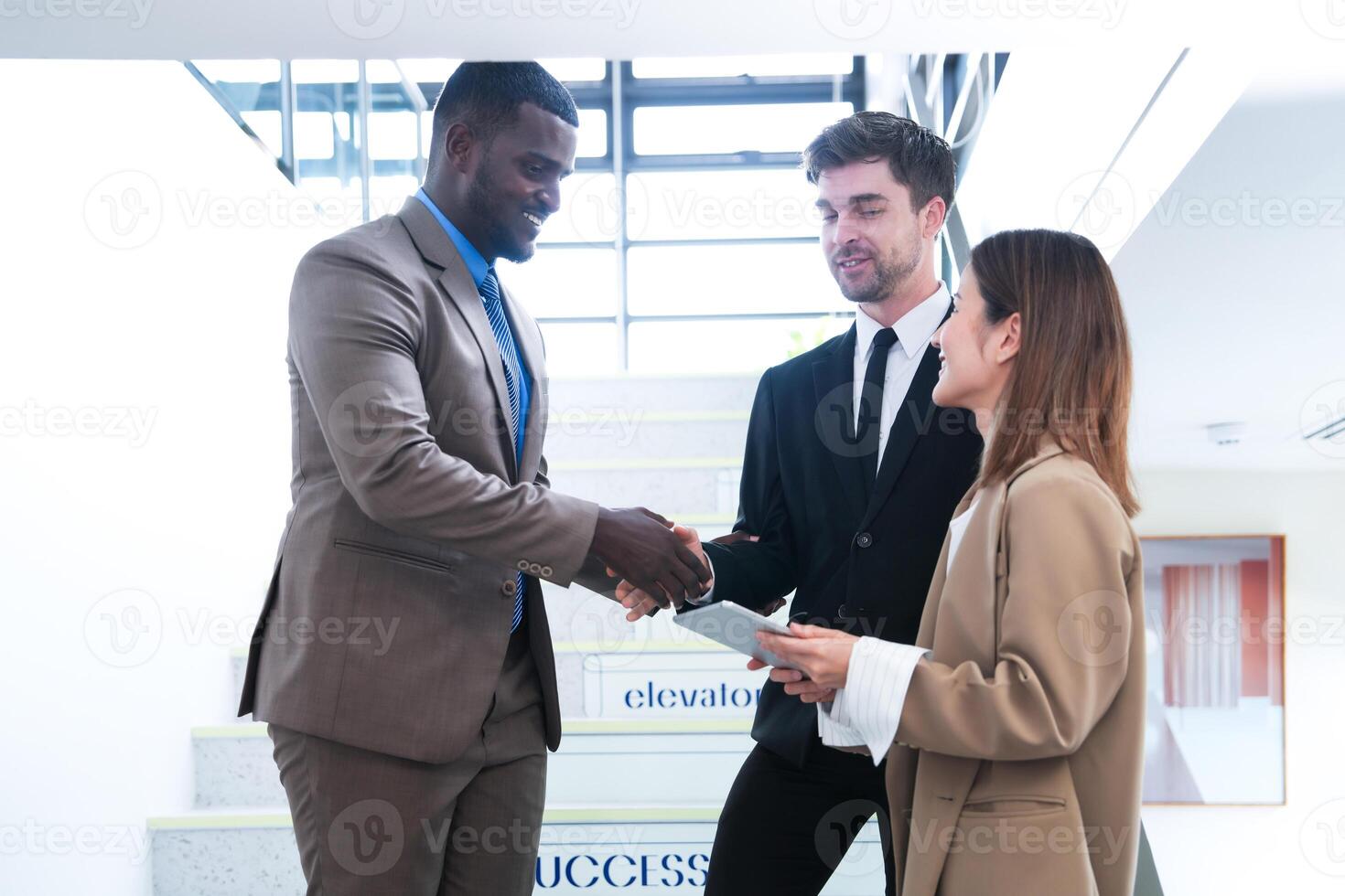 Business people shaking hands. finishing up a meeting. team of business people walk in rush hour at indoor pedestrian stairs and talk together. concept negotiations in feeling successful and happy. photo