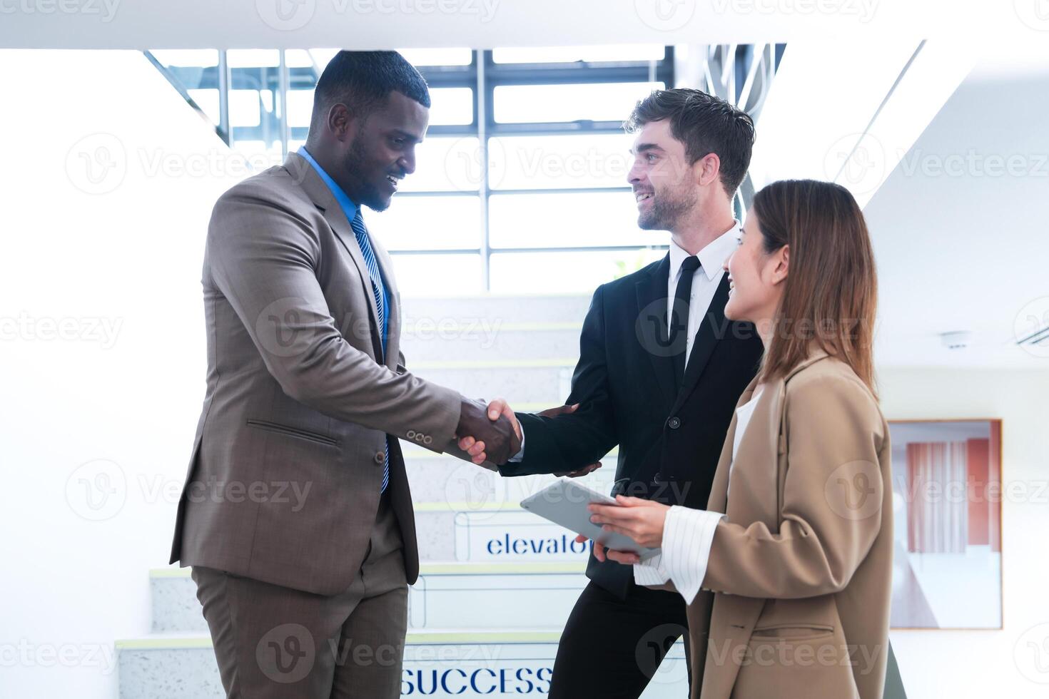 Business people shaking hands. finishing up a meeting. team of business people walk in rush hour at indoor pedestrian stairs and talk together. concept negotiations in feeling successful and happy. photo