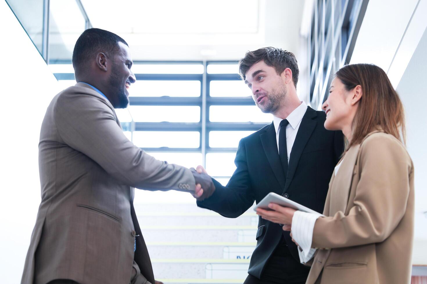 Business people shaking hands. finishing up a meeting. team of business people walk in rush hour at indoor pedestrian stairs and talk together. concept negotiations in feeling successful and happy. photo