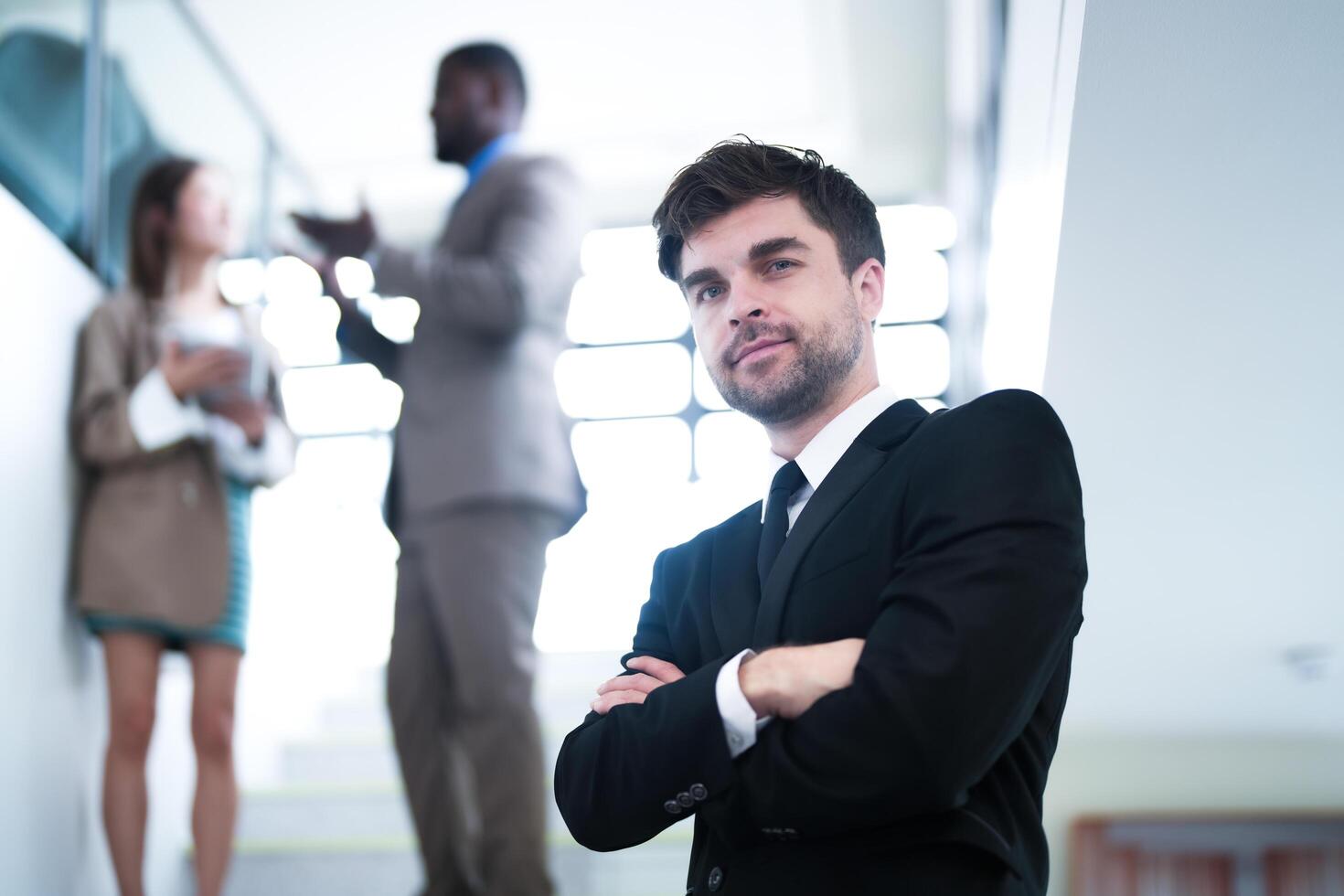 business people and office concept. happy smiling businessman in dark suit. Portrait of smiling mid adult businessman standing at corporate office. Businessman smiling with arms crossed in office. photo