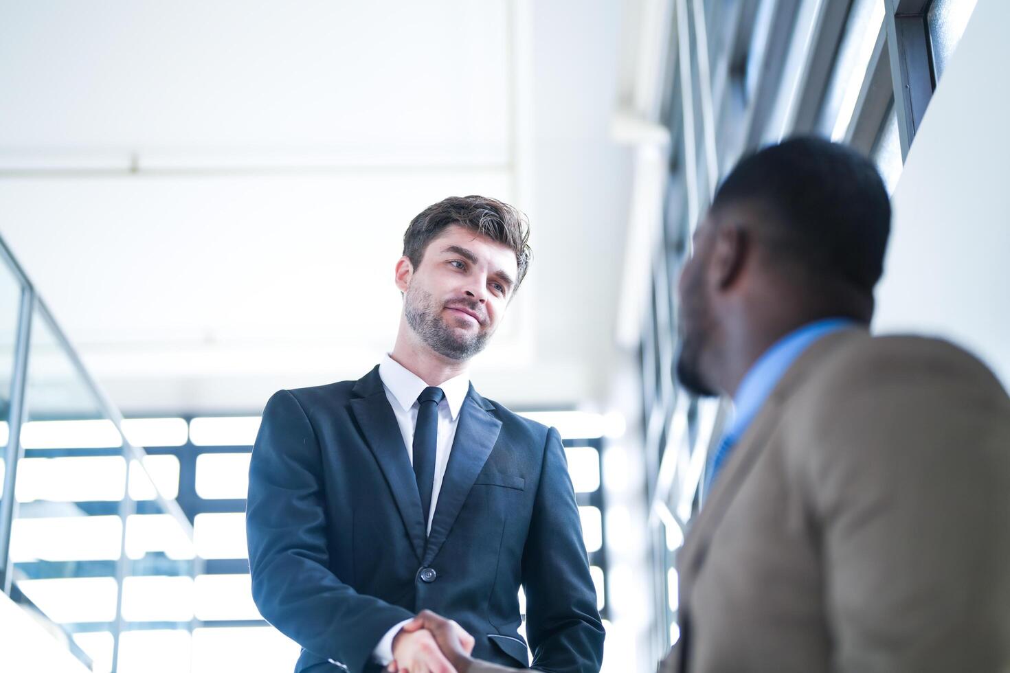 Business people shaking hands. finishing up a meeting. team of business people walk in rush hour at indoor pedestrian stairs and talk together. concept negotiations in feeling successful and happy. photo