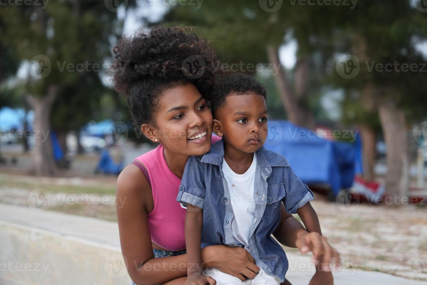 Mixed race African and Asian mother and boy is playing at the outdoor area. smiling happy family have fun running on the beach. portrait of mom and kid lifestyle with a unique hairstyle. photo