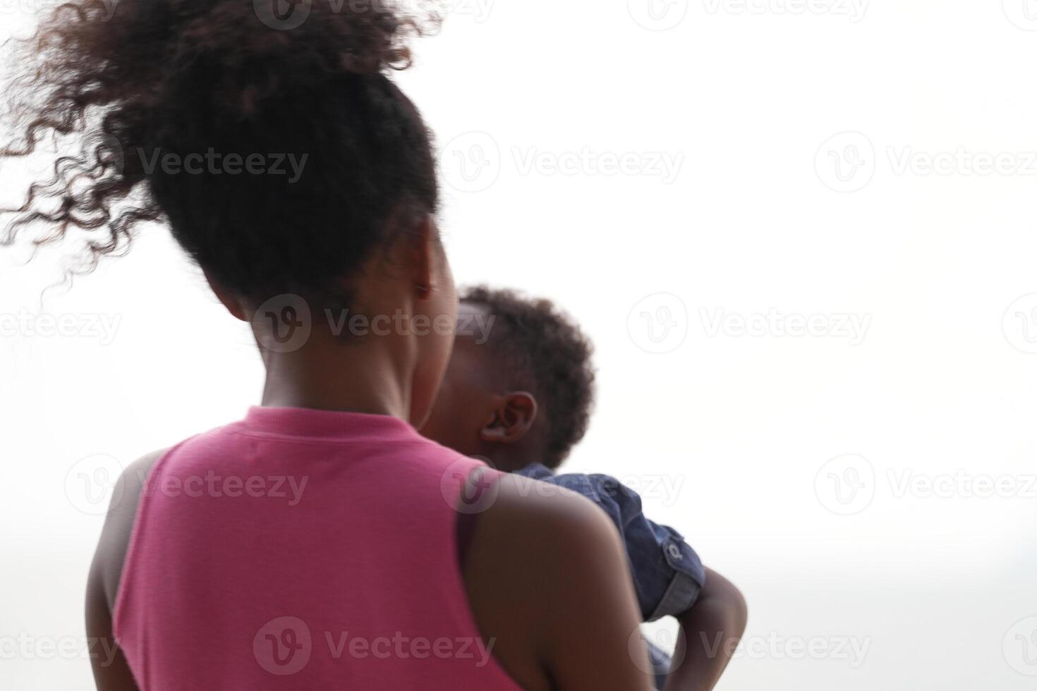 Mixed race African and Asian mother and boy is playing at the outdoor area. smiling happy family have fun running on the beach. portrait of mom and kid lifestyle with a unique hairstyle. photo