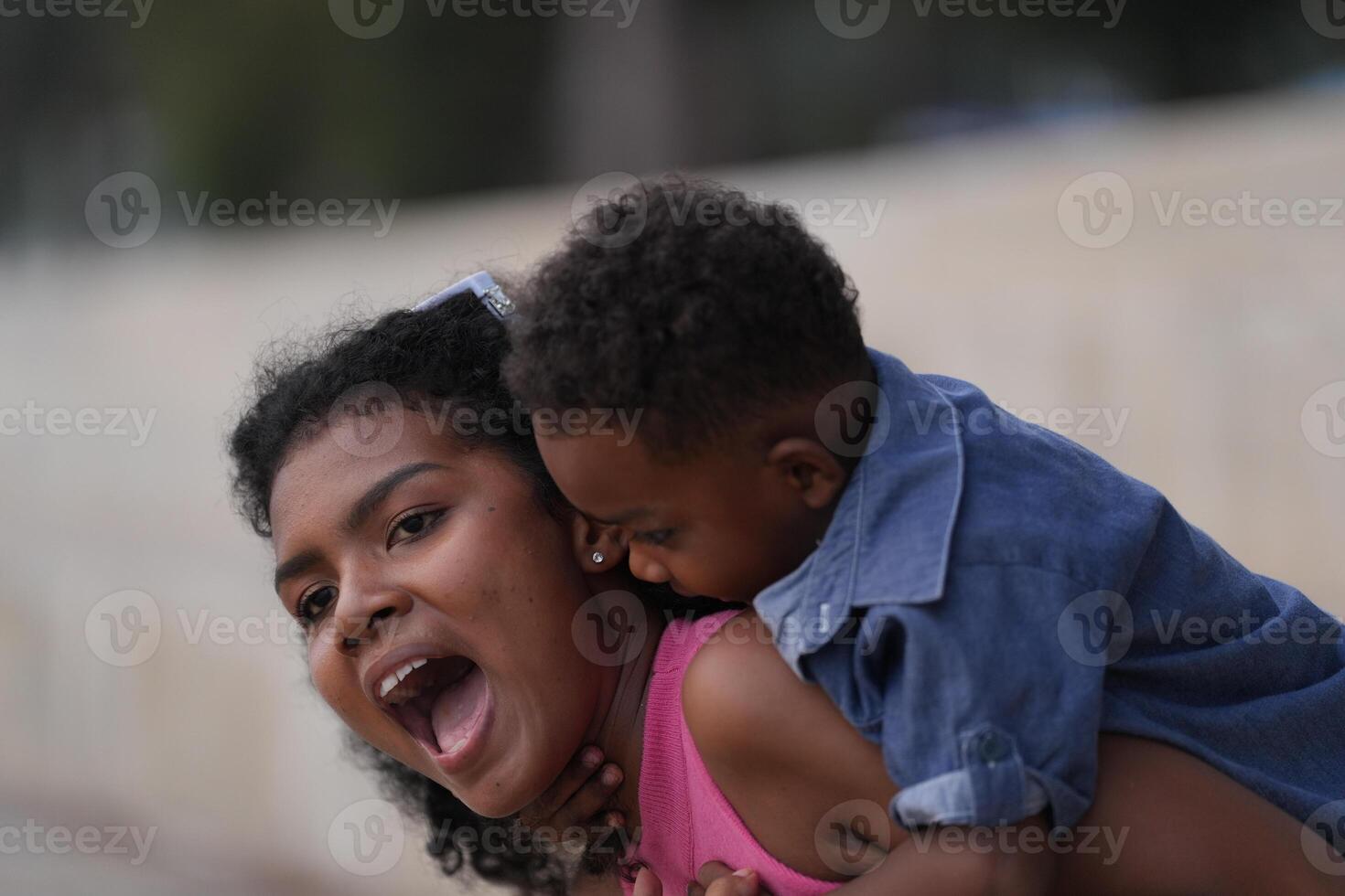 Mixed race African and Asian mother and boy is playing at the outdoor area. smiling happy family have fun running on the beach. portrait of mom and kid lifestyle with a unique hairstyle. photo