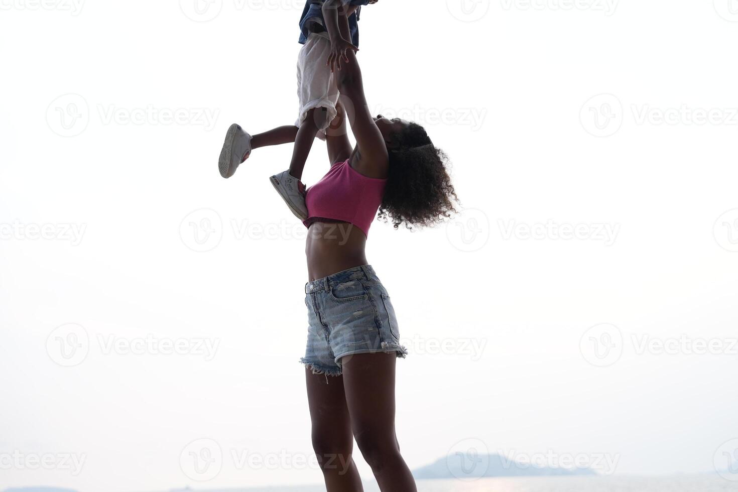 Mixed race African and Asian mother and boy is playing at the outdoor area. smiling happy family have fun running on the beach. portrait of mom and kid lifestyle with a unique hairstyle. photo