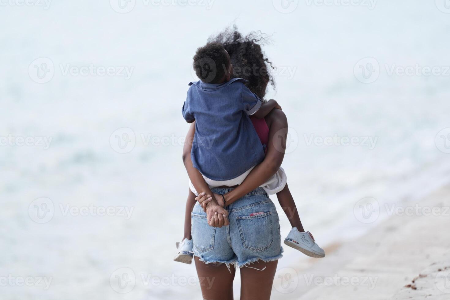 Mixed race African and Asian mother and boy is playing at the outdoor area. smiling happy family have fun running on the beach. portrait of mom and kid lifestyle with a unique hairstyle. photo