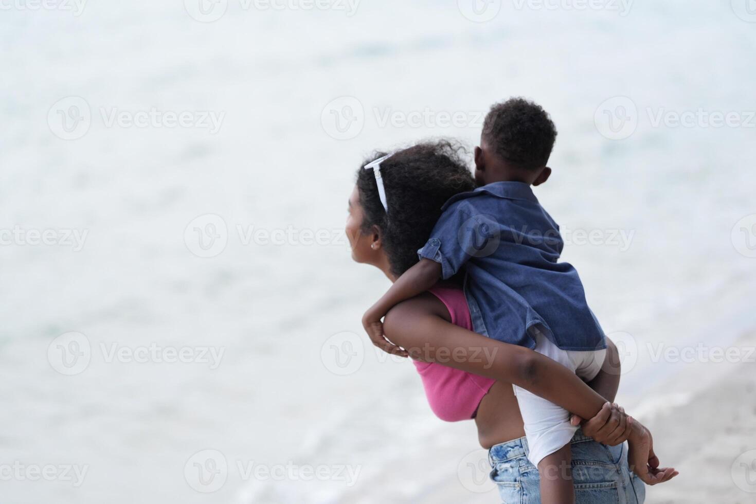 Mixed race African and Asian mother and boy is playing at the outdoor area. smiling happy family have fun running on the beach. portrait of mom and kid lifestyle with a unique hairstyle. photo