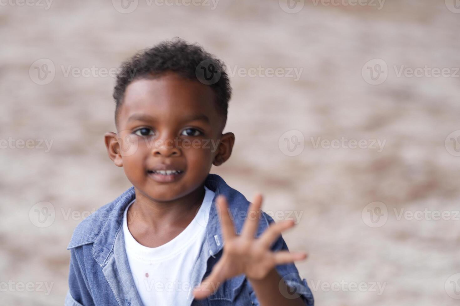 mezclado carrera africano y asiático chico es jugando a el al aire libre área. sonriente contento chico tiene divertido corriendo en el playa. retrato de chico estilo de vida con un único peinado. foto