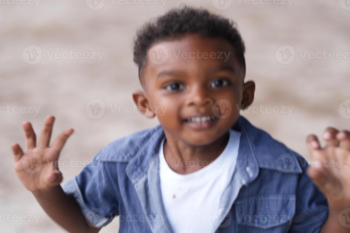 mezclado carrera africano y asiático chico es jugando a el al aire libre área. sonriente contento chico tiene divertido corriendo en el playa. retrato de chico estilo de vida con un único peinado. foto