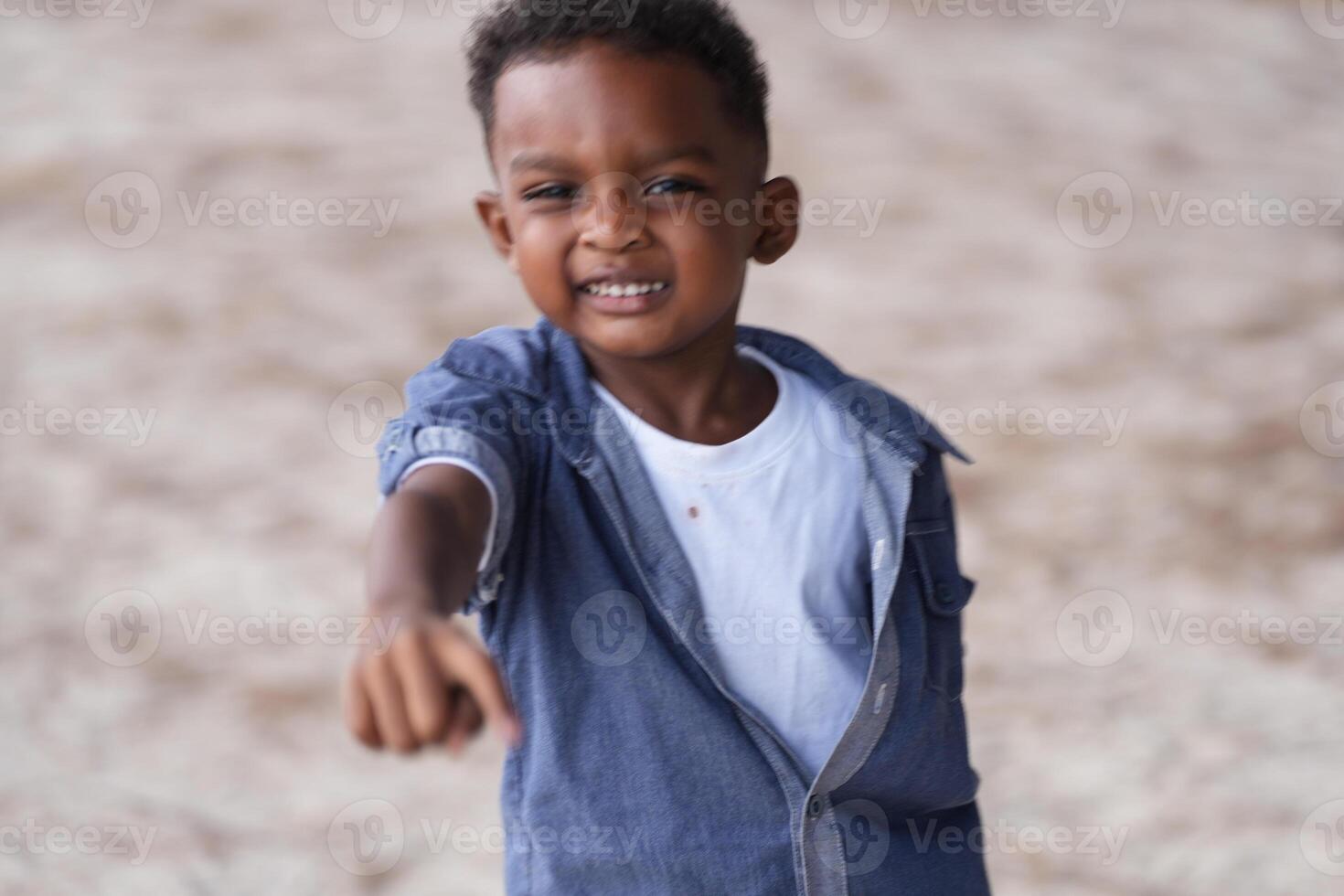 mezclado carrera africano y asiático chico es jugando a el al aire libre área. sonriente contento chico tiene divertido corriendo en el playa. retrato de chico estilo de vida con un único peinado. foto