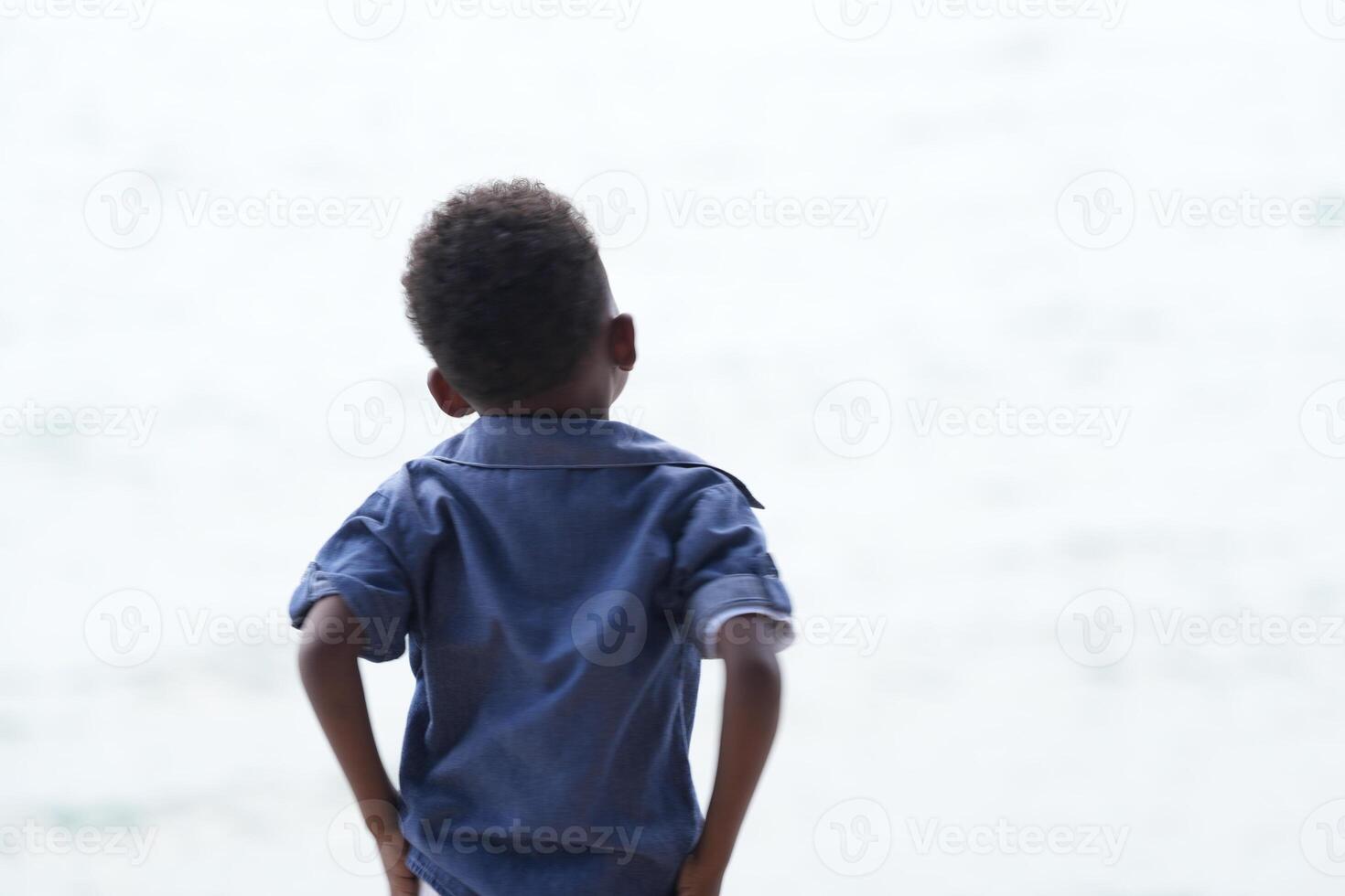 Mixed race African and Asian boy is playing at the outdoor area. smiling happy boy has fun running on the beach. portrait of boy lifestyle with a unique hairstyle. photo