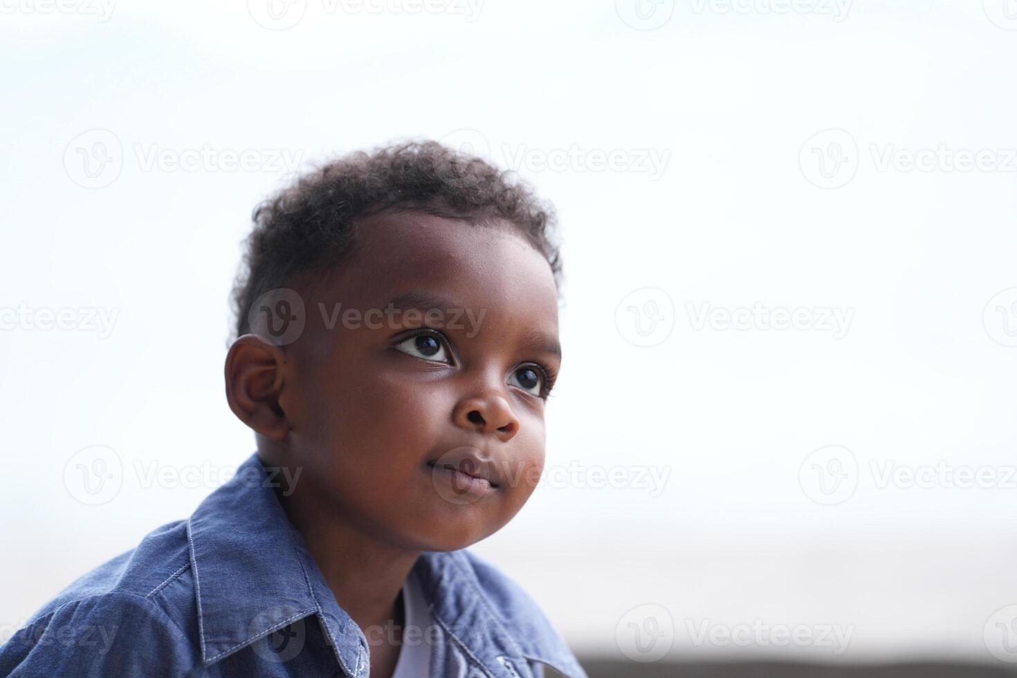 Mixed race African and Asian boy is playing at the outdoor area. smiling happy boy has fun running on the beach. portrait of boy lifestyle with a unique hairstyle. photo