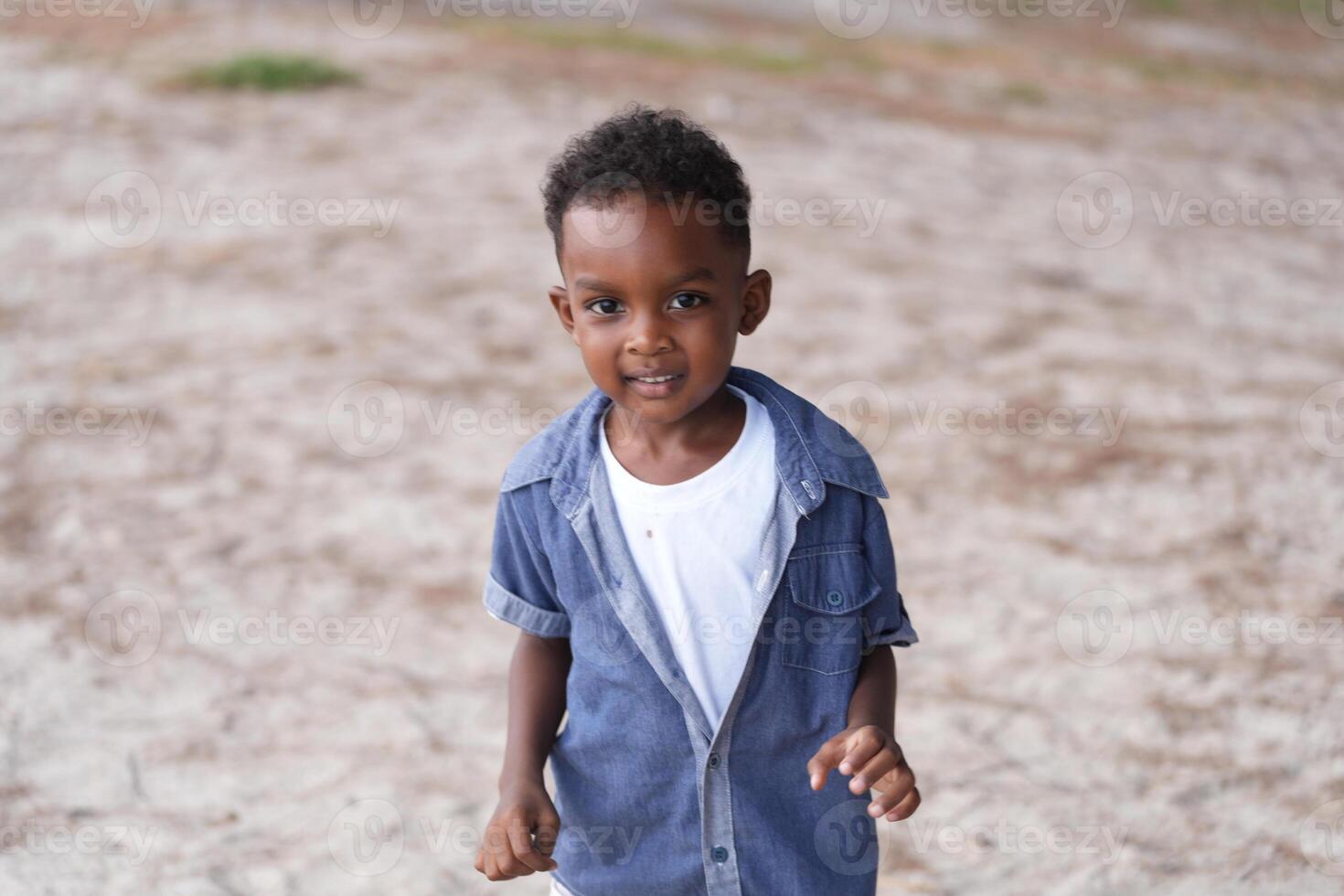 Mixed race African and Asian boy is playing at the outdoor area. smiling happy boy has fun running on the beach. portrait of boy lifestyle with a unique hairstyle. photo