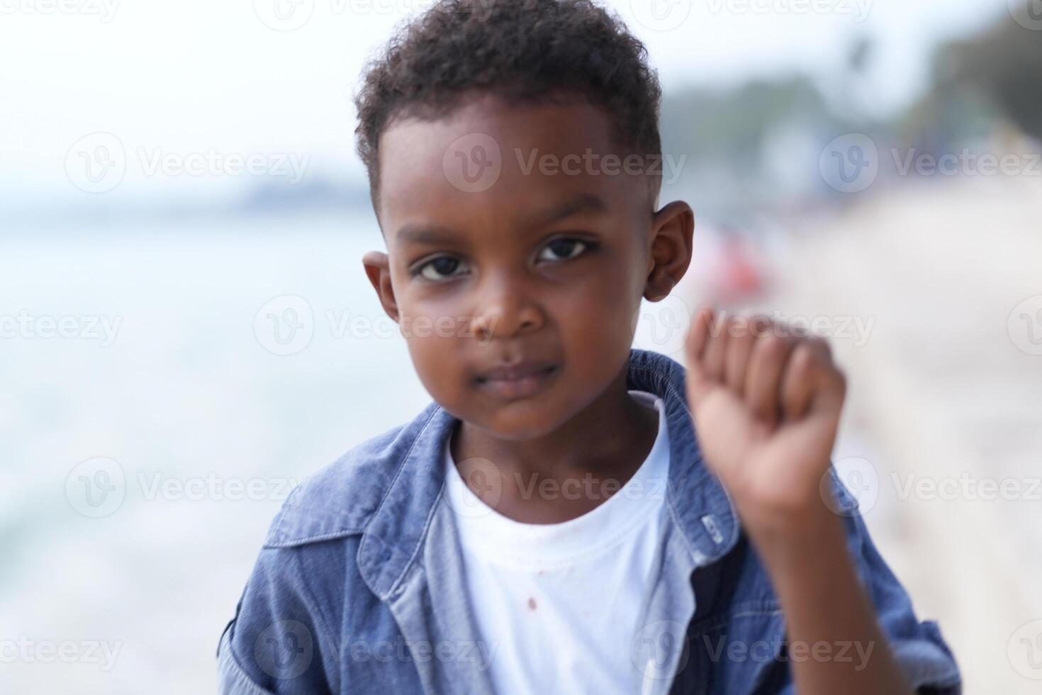 Mixed race African and Asian boy is playing at the outdoor area. smiling happy boy has fun running on the beach. portrait of boy lifestyle with a unique hairstyle. photo