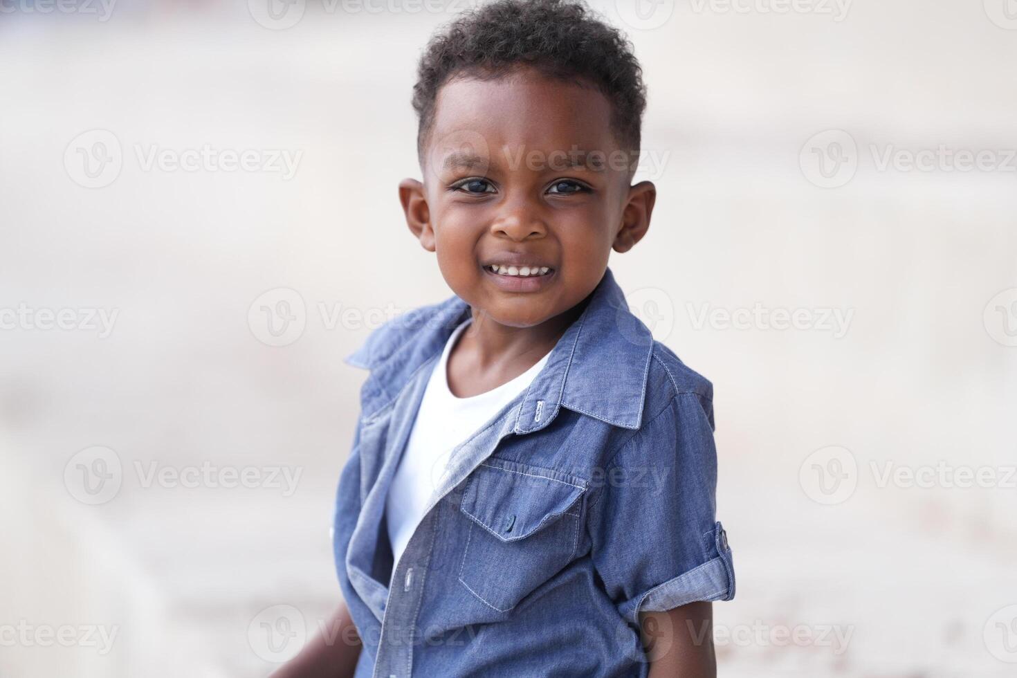 mezclado carrera africano y asiático chico es jugando a el al aire libre área. sonriente contento chico tiene divertido corriendo en el playa. retrato de chico estilo de vida con un único peinado. foto