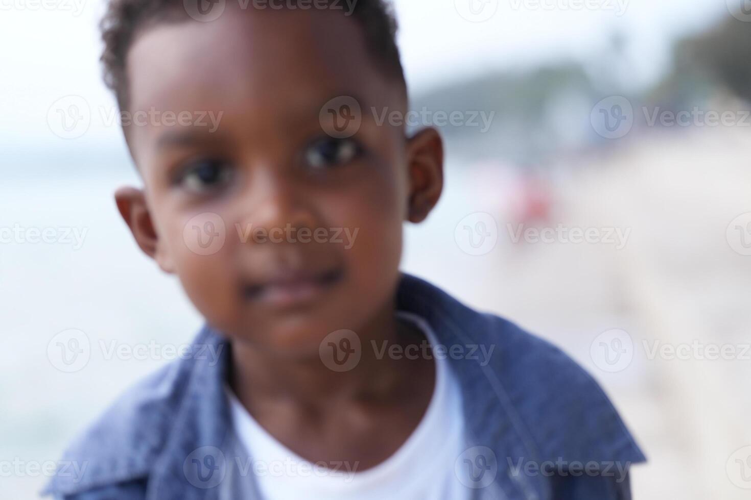 mezclado carrera africano y asiático chico es jugando a el al aire libre área. sonriente contento chico tiene divertido corriendo en el playa. retrato de chico estilo de vida con un único peinado. foto