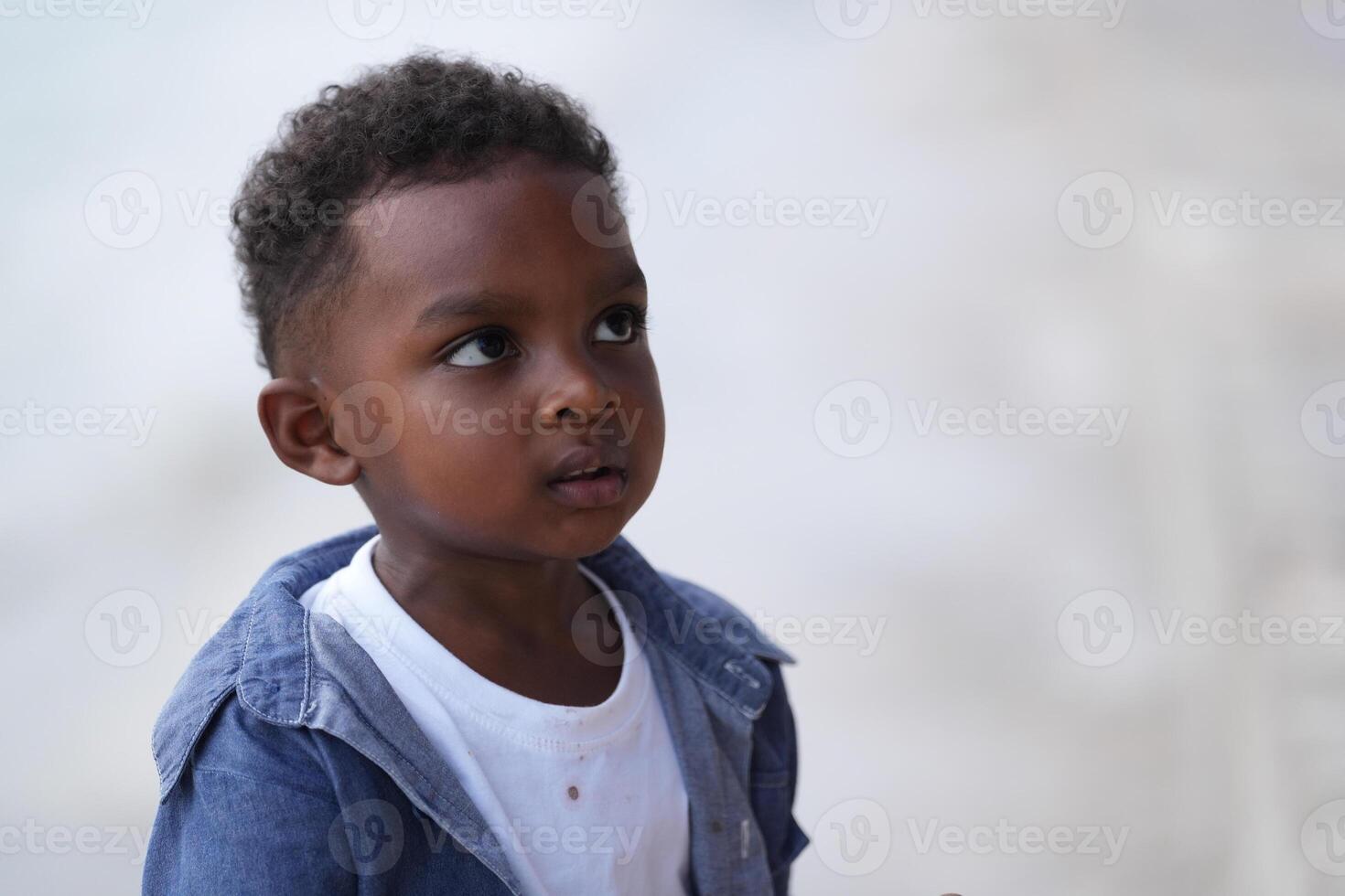 mezclado carrera africano y asiático chico es jugando a el al aire libre área. sonriente contento chico tiene divertido corriendo en el playa. retrato de chico estilo de vida con un único peinado. foto