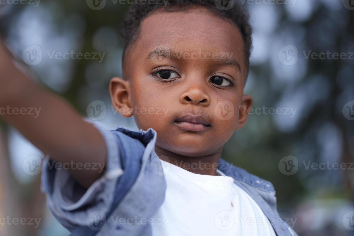 mezclado carrera africano y asiático chico es jugando a el al aire libre área. sonriente contento chico tiene divertido corriendo en el playa. retrato de chico estilo de vida con un único peinado. foto