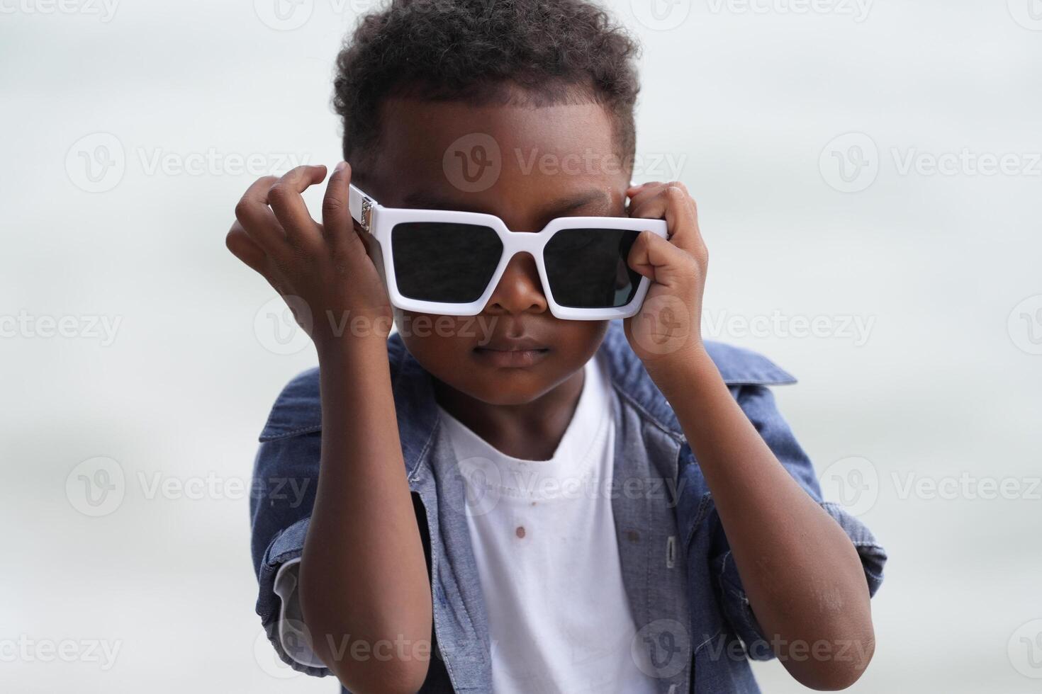 Mixed race African and Asian boy is playing at the outdoor area. smiling happy boy has fun running on the beach. portrait of boy lifestyle with a unique hairstyle. photo