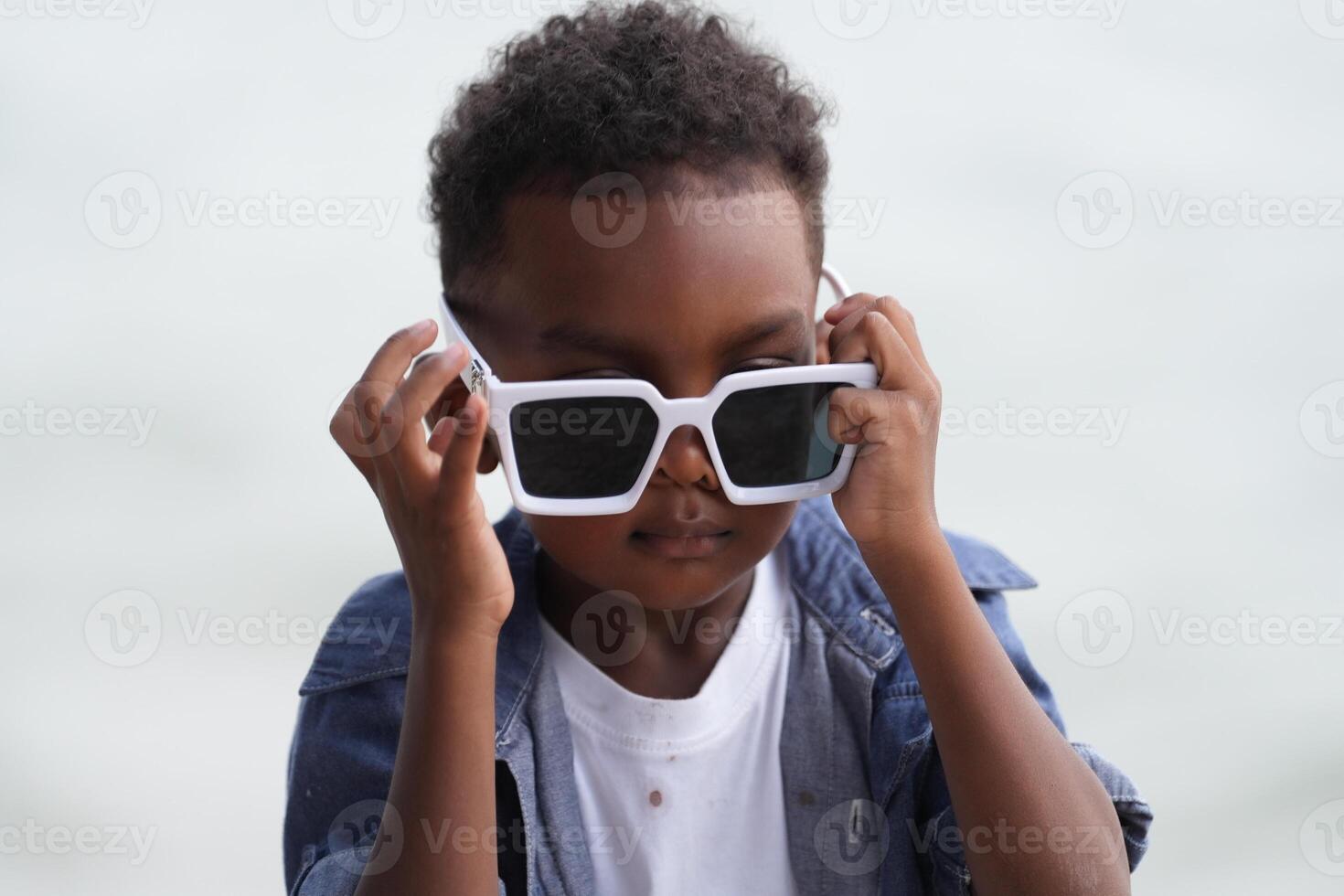 Mixed race African and Asian boy is playing at the outdoor area. smiling happy boy has fun running on the beach. portrait of boy lifestyle with a unique hairstyle. photo