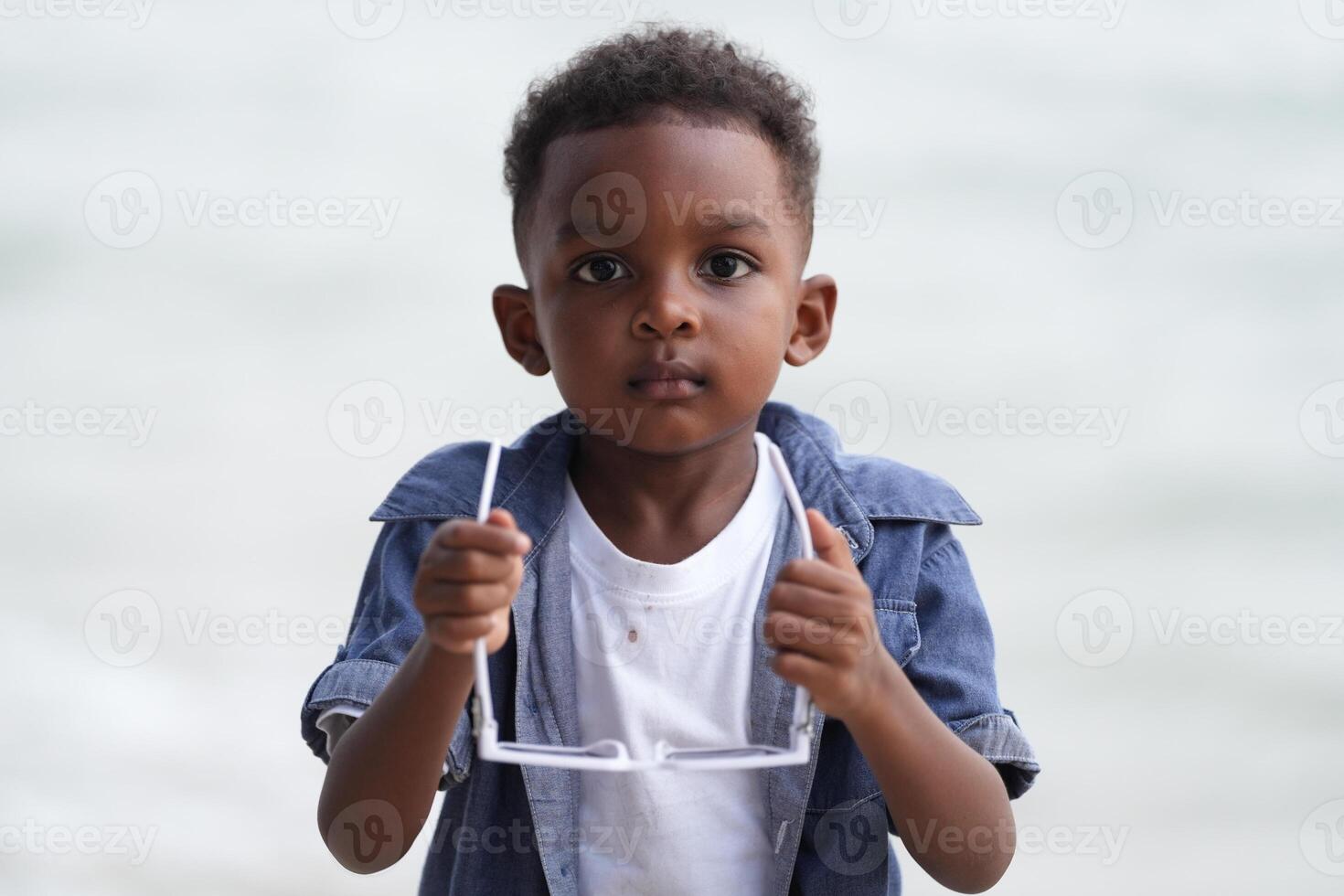 Mixed race African and Asian boy is playing at the outdoor area. smiling happy boy has fun running on the beach. portrait of boy lifestyle with a unique hairstyle. photo