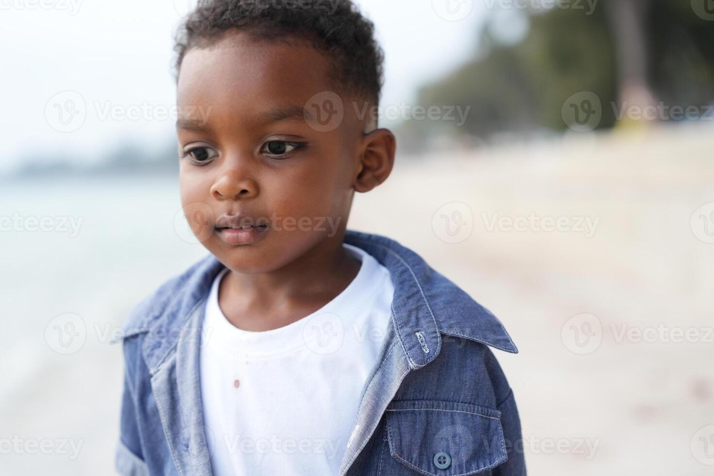 Mixed race African and Asian boy is playing at the outdoor area. smiling happy boy has fun running on the beach. portrait of boy lifestyle with a unique hairstyle. photo