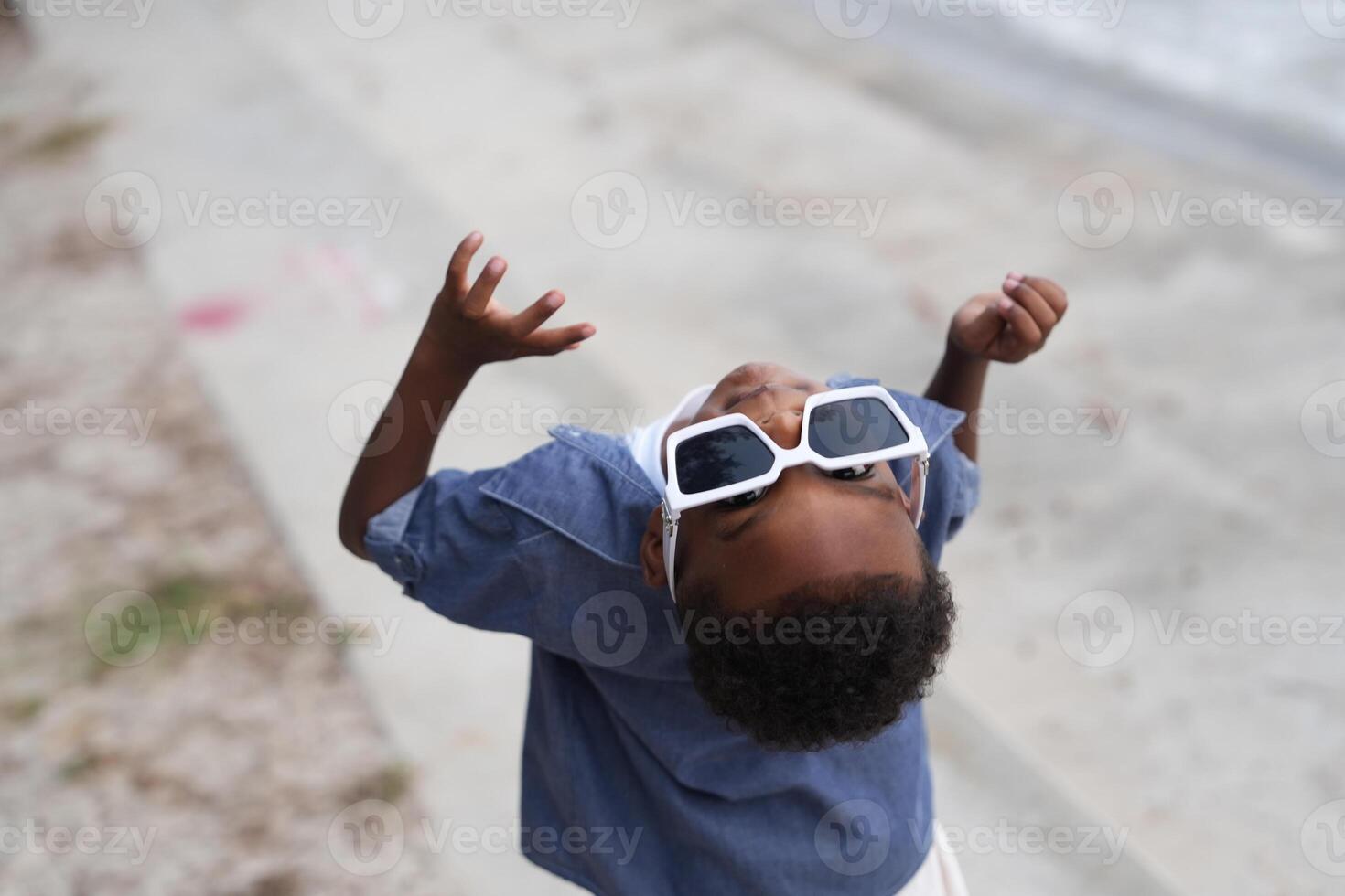 Mixed race African and Asian boy is playing at the outdoor area. smiling happy boy has fun running on the beach. portrait of boy lifestyle with a unique hairstyle. photo