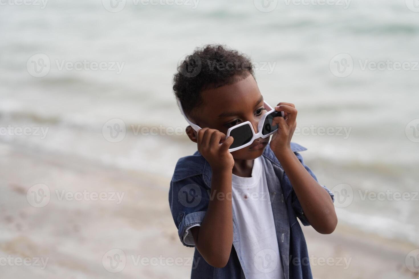 Mixed race African and Asian boy is playing at the outdoor area. smiling happy boy has fun running on the beach. portrait of boy lifestyle with a unique hairstyle. photo