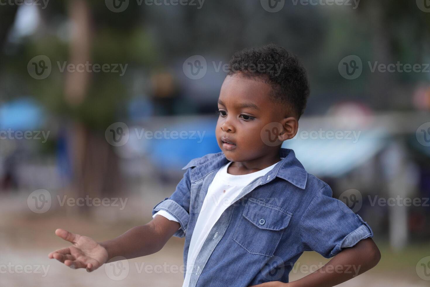 Mixed race African and Asian boy is playing at the outdoor area. smiling happy boy has fun running on the beach. portrait of boy lifestyle with a unique hairstyle. photo