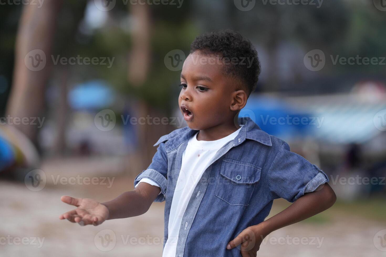 mezclado carrera africano y asiático chico es jugando a el al aire libre área. sonriente contento chico tiene divertido corriendo en el playa. retrato de chico estilo de vida con un único peinado. foto