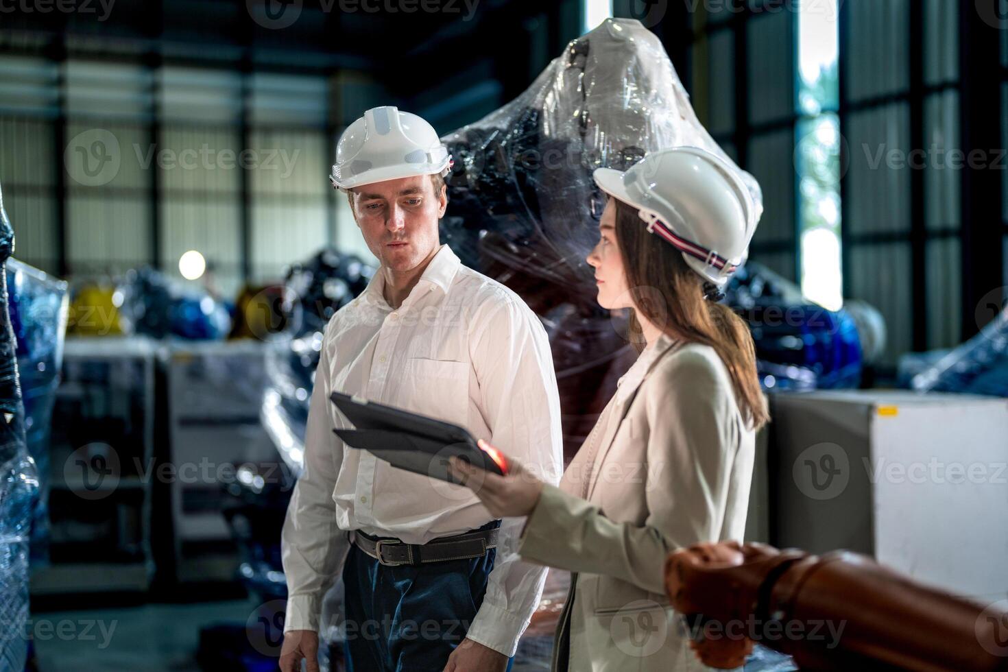 Business engineers meeting and checking new machine robot. Workers walking at warehouse industry welding machine. business negotiation concepts and technology. women Using smart Tablet to present man. photo